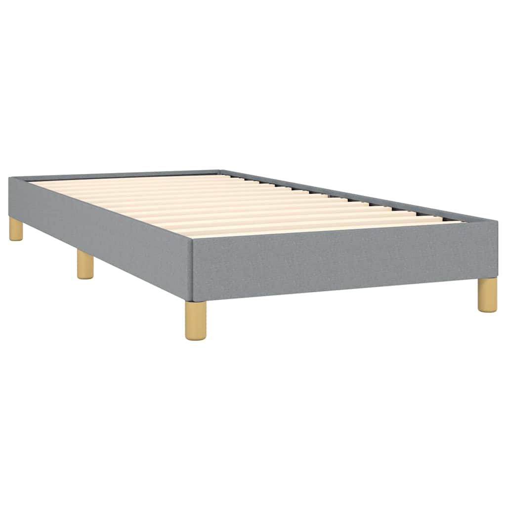 Grey upholstered single bed frame with white mattress and golden legs