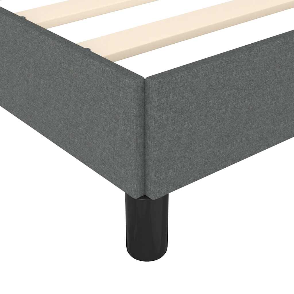 Closeup of a grey upholstered bed frame corner with wooden slats and a black leg