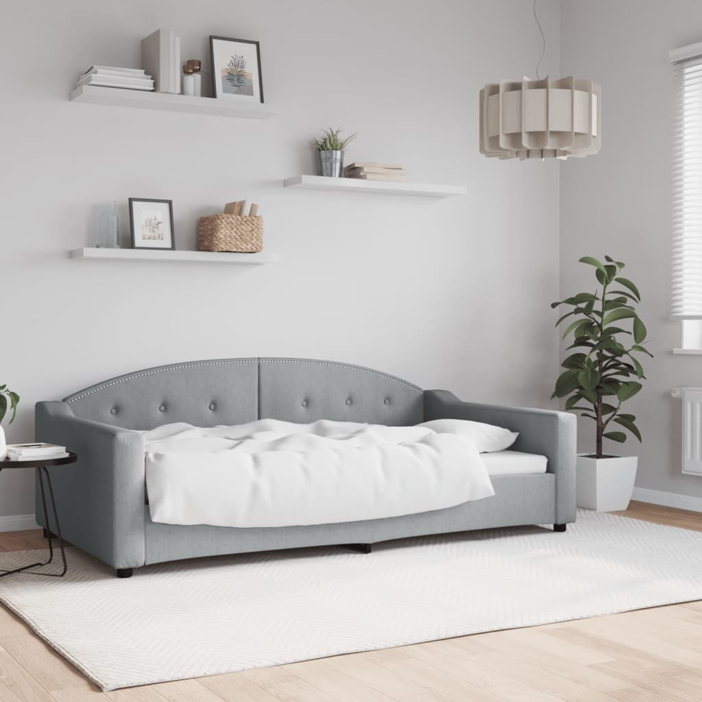 Grey upholstered daybed with tufted back and studded trim