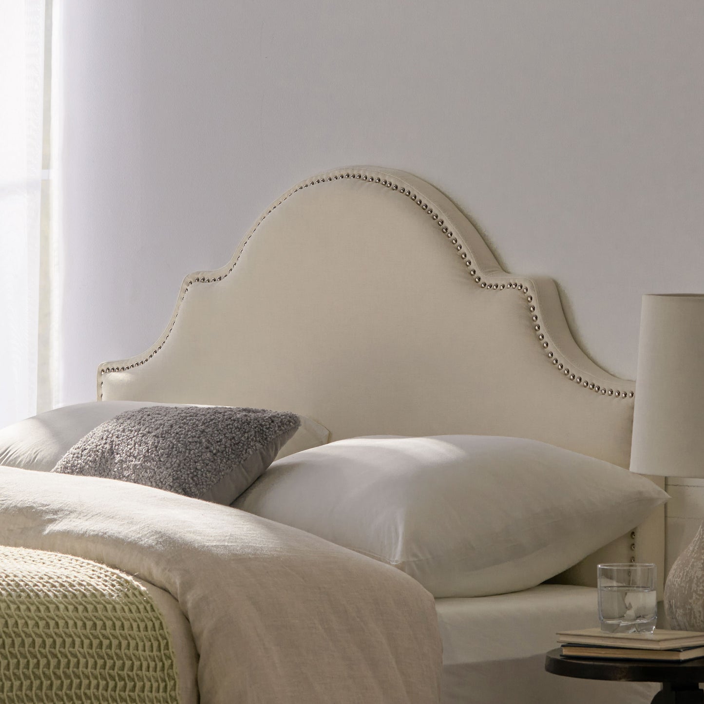 Cream upholstered headboard with silver nailhead trim