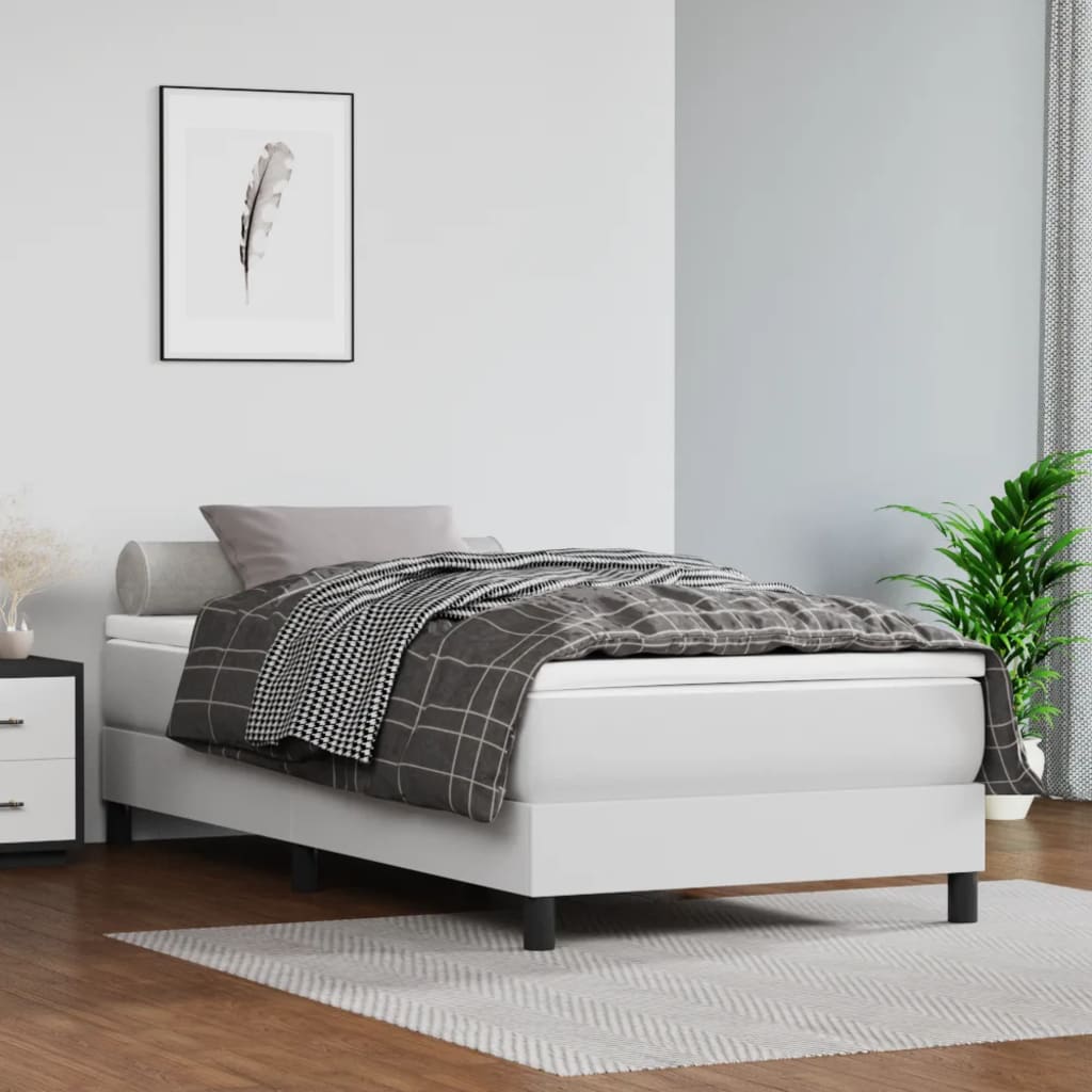 White upholstered twin bed frame with a grey patterned duvet and lumbar pillow