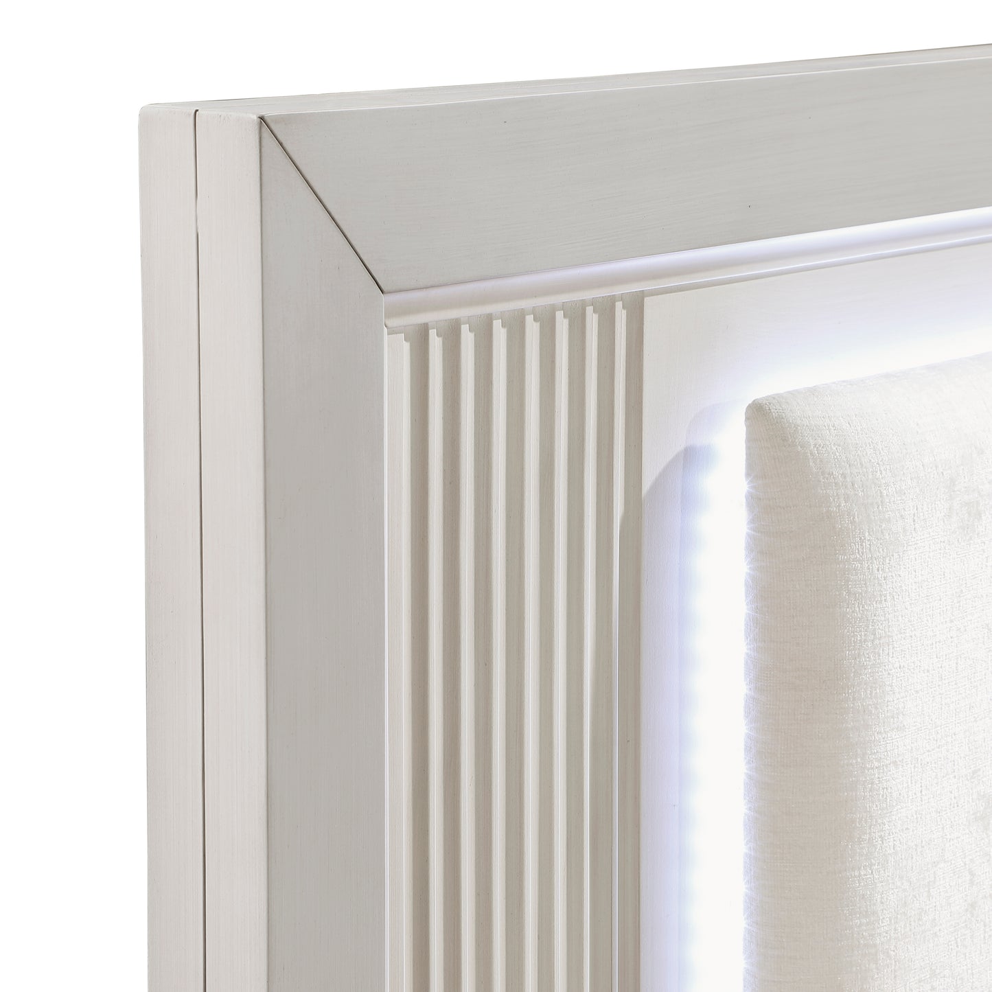 Closeup of a light wood frame with vertical fluting detail and embedded LED lighting on a white upholstered headboard