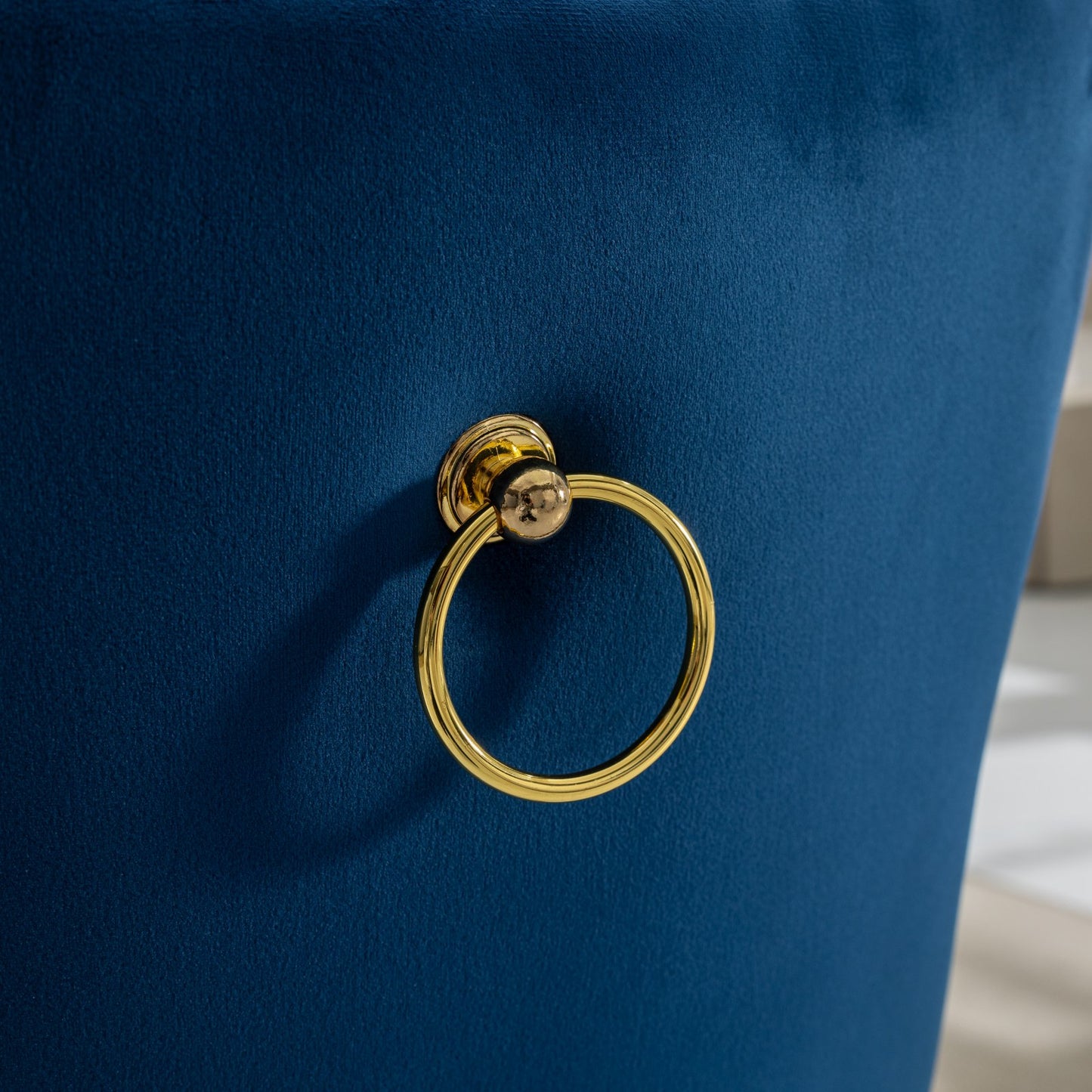 Closeup of navy blue velvet chair back with gold ring pull