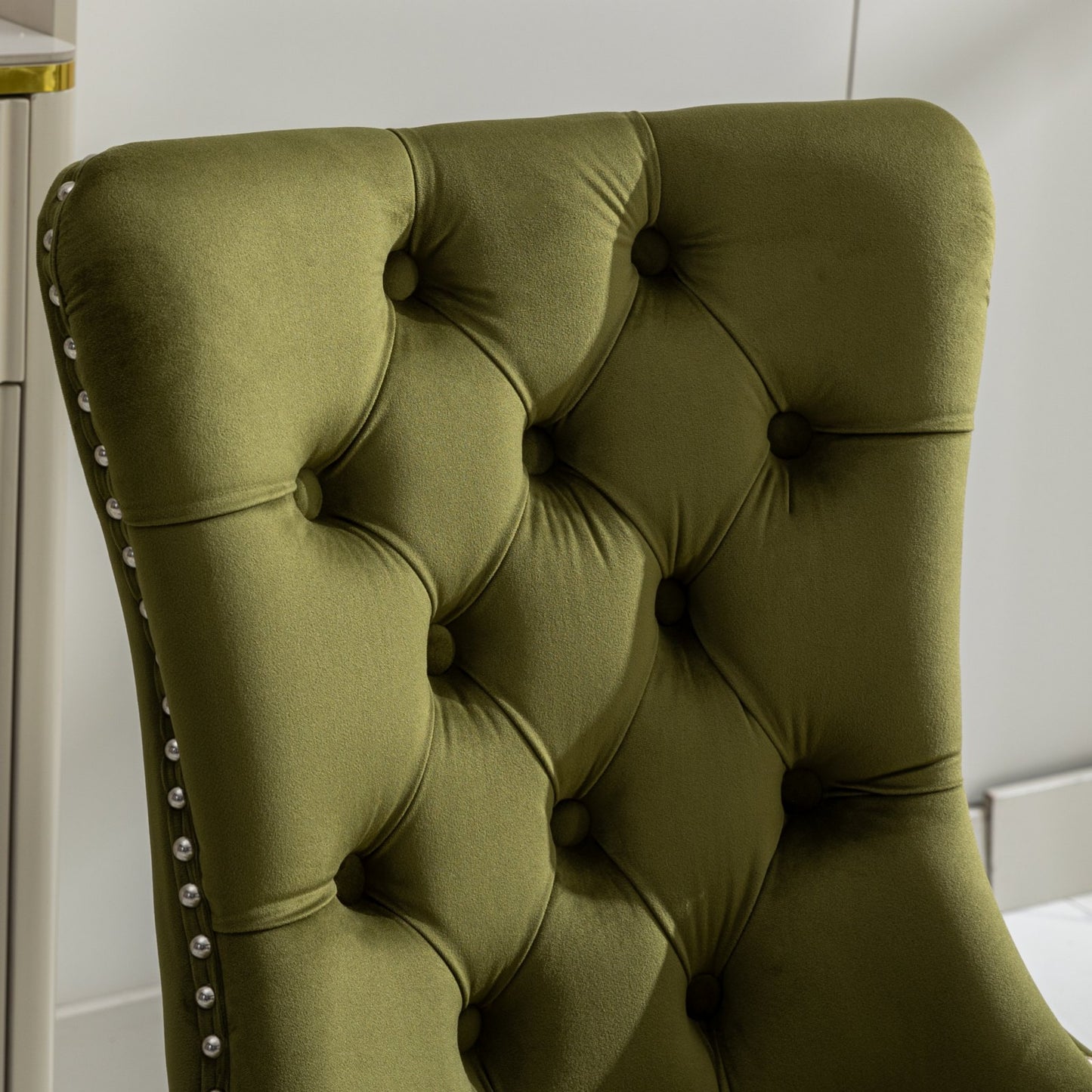 Olive green velvet dining chair with button tufting and silver nailhead trim