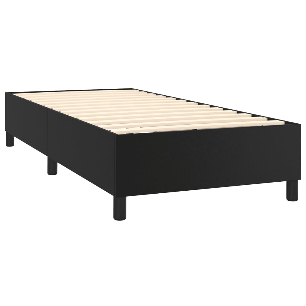 Black upholstered divan bed base with white mattress on dark wooden legs