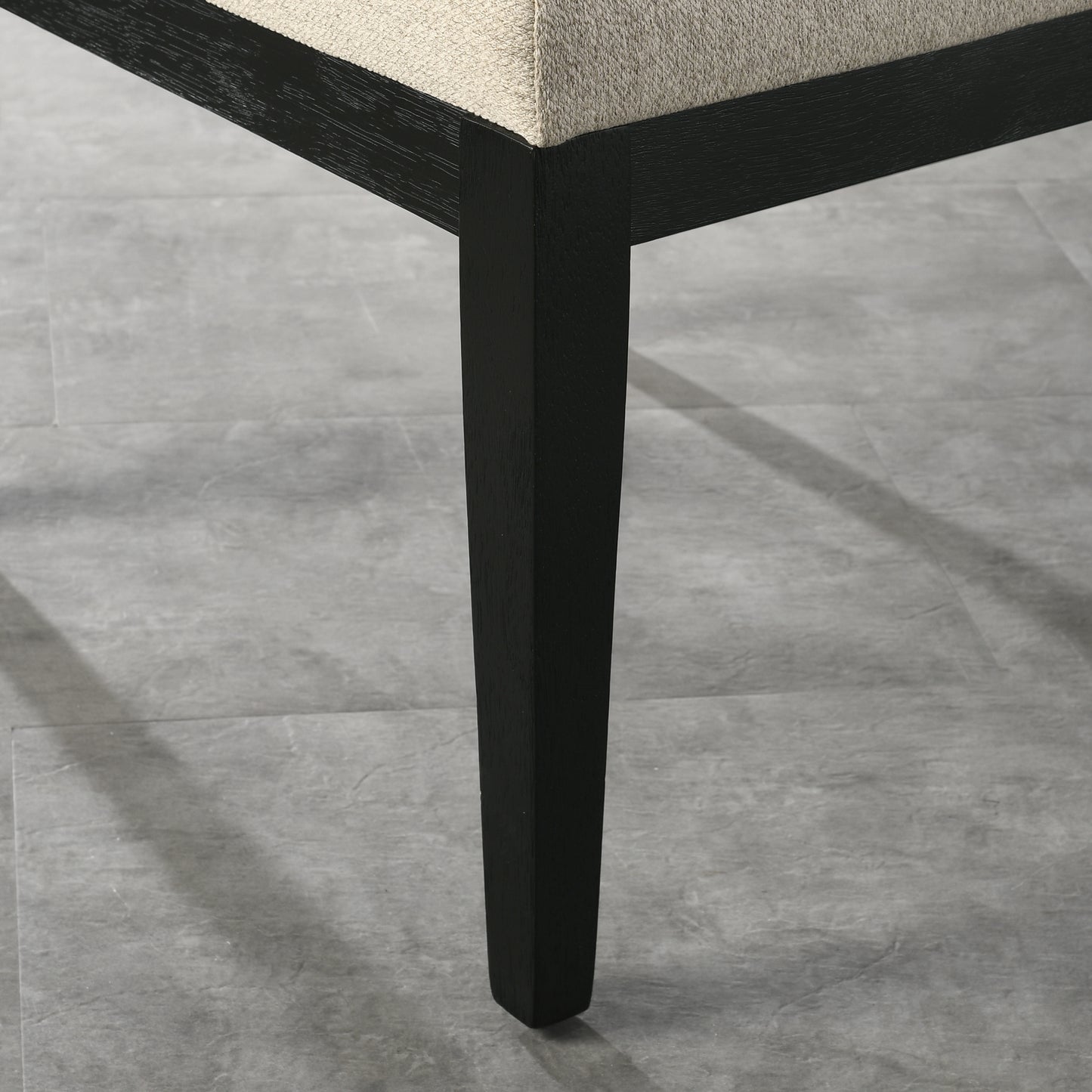 Black wood chair leg with textured beige upholstery detail