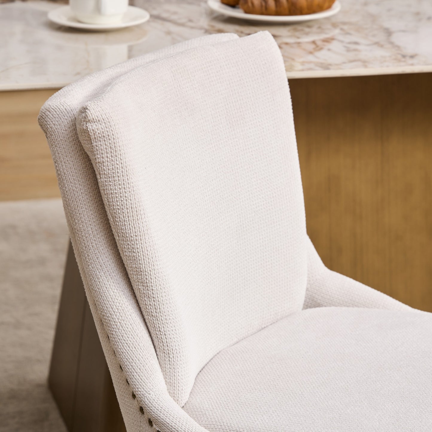 Cream upholstered accent chair with textured fabric and brass nailhead trim