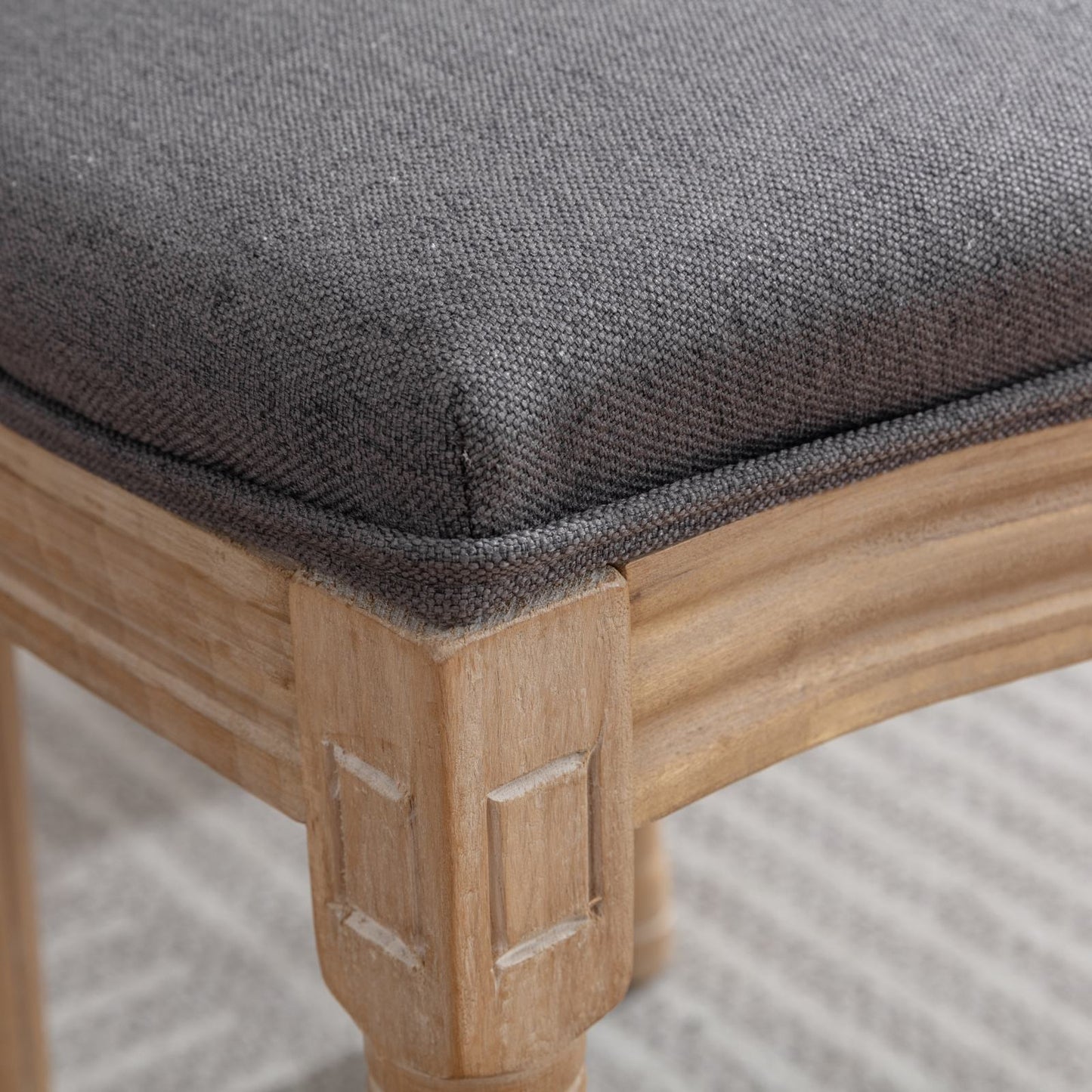 Closeup of dark gray fabric upholstered seat on a light wood accent chair