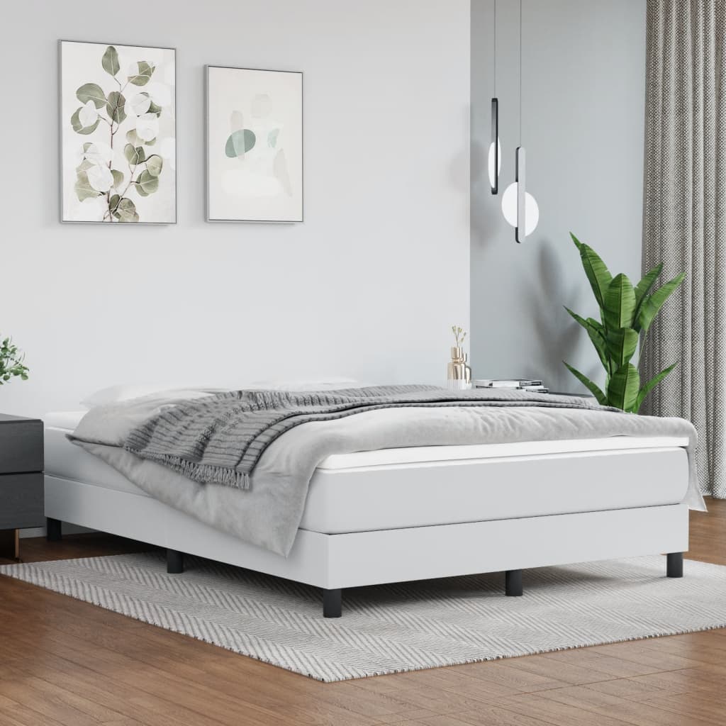 White upholstered bed frame with black legs and a grey throw blanket