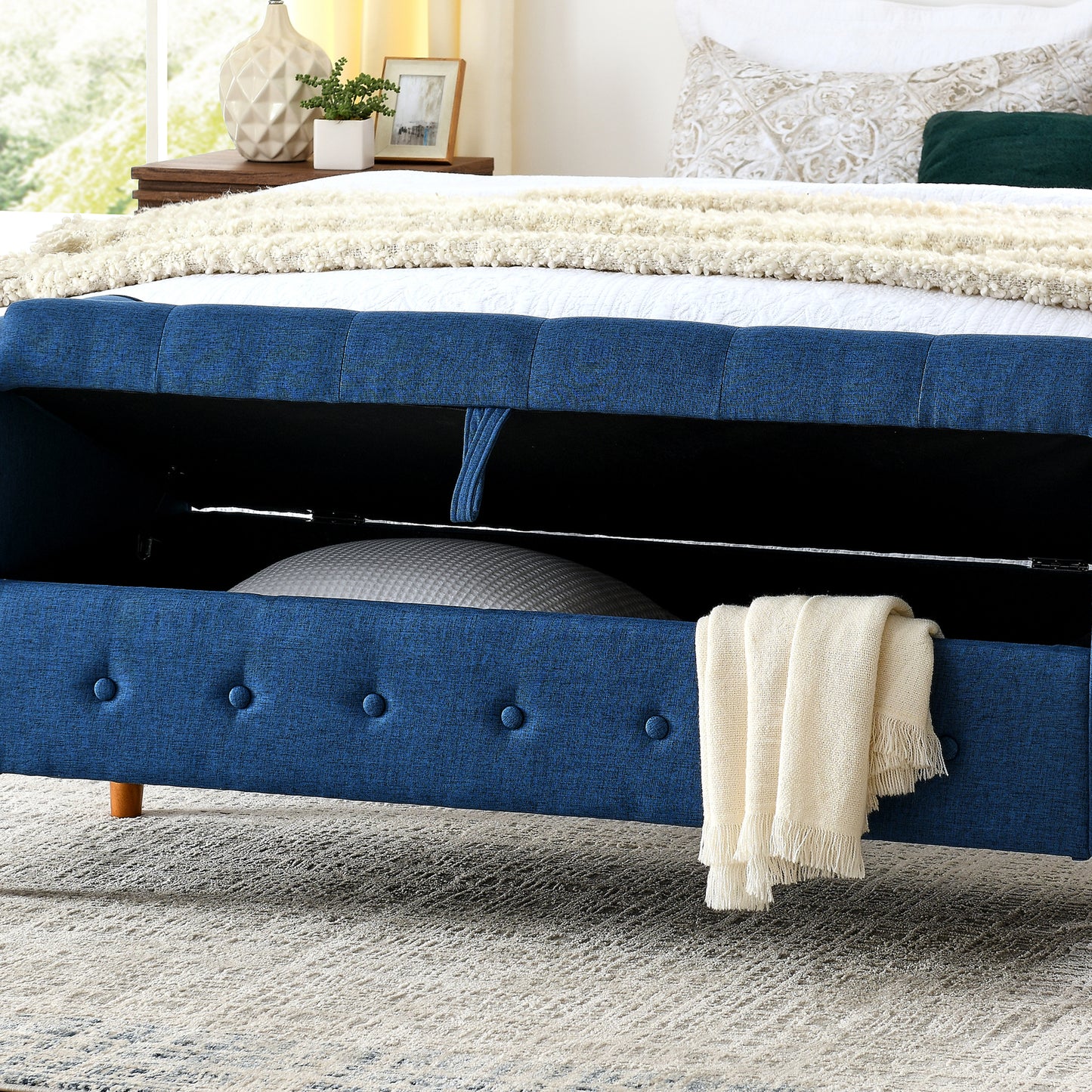 Blue upholstered storage bed with button tufting and open compartment