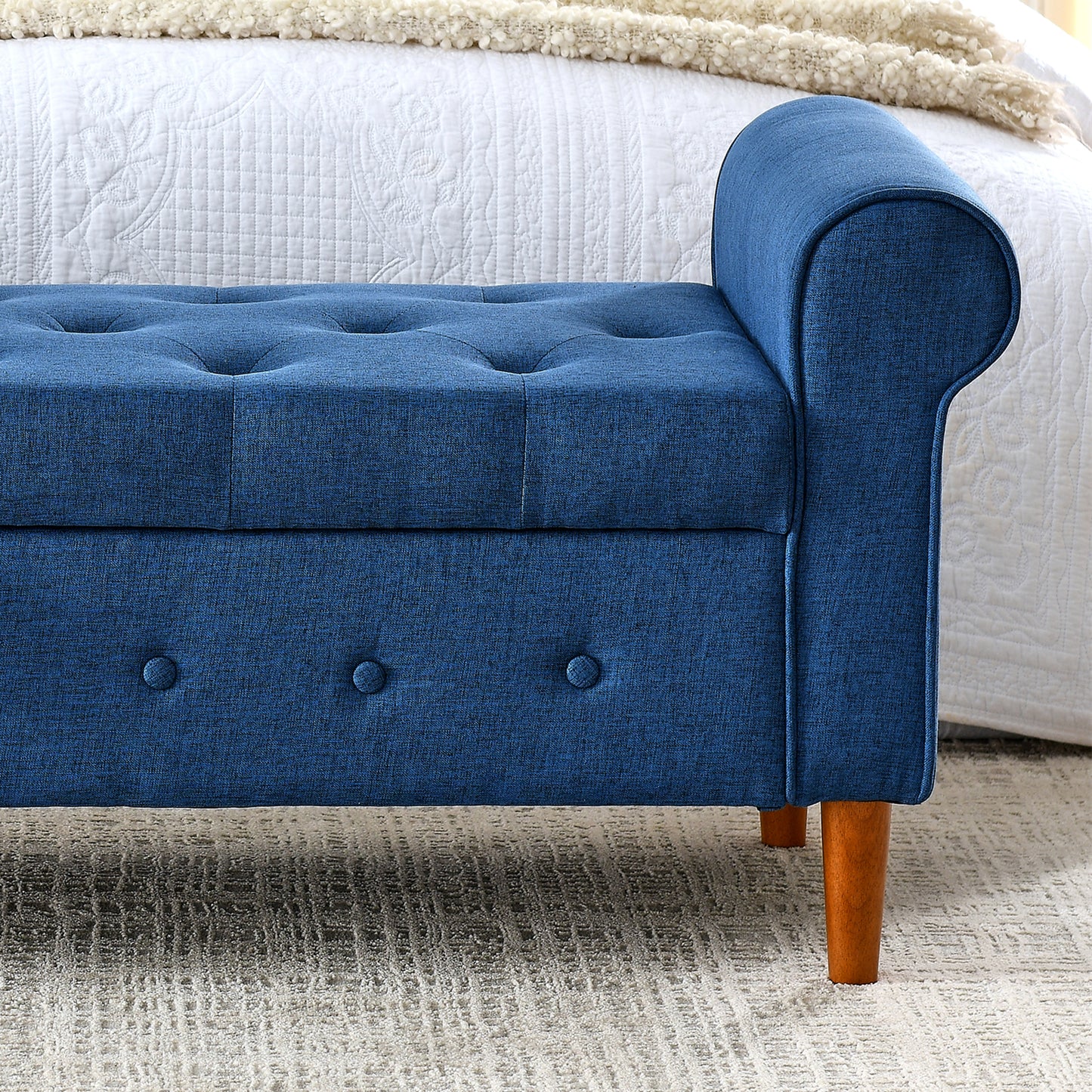 Deep blue linen upholstered storage bench with tufted seat and scrolled arms