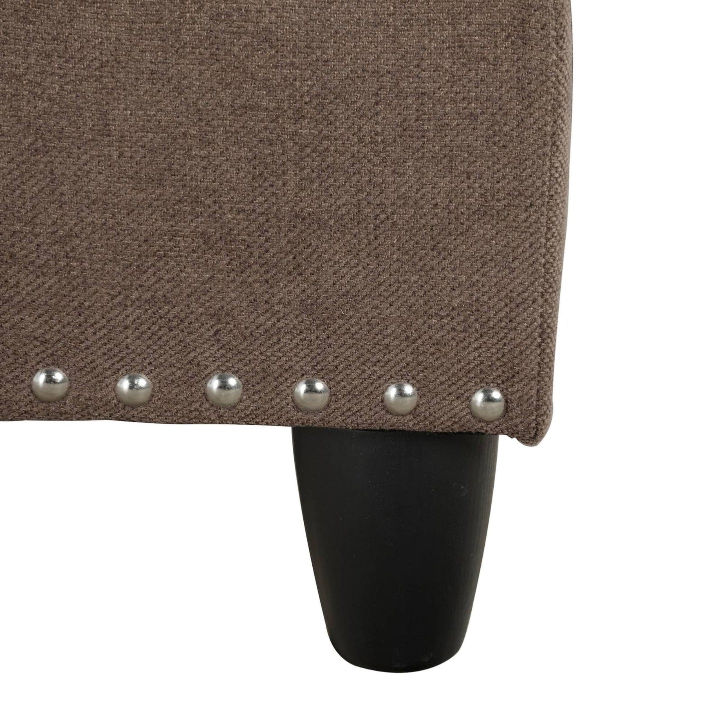 Closeup of brown textured fabric with nailhead trim and a black tapered leg