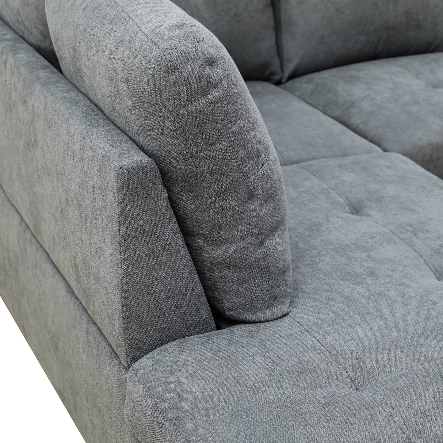 Closeup of plush grey fabric sectional sofa armrest and tufted seat cushion