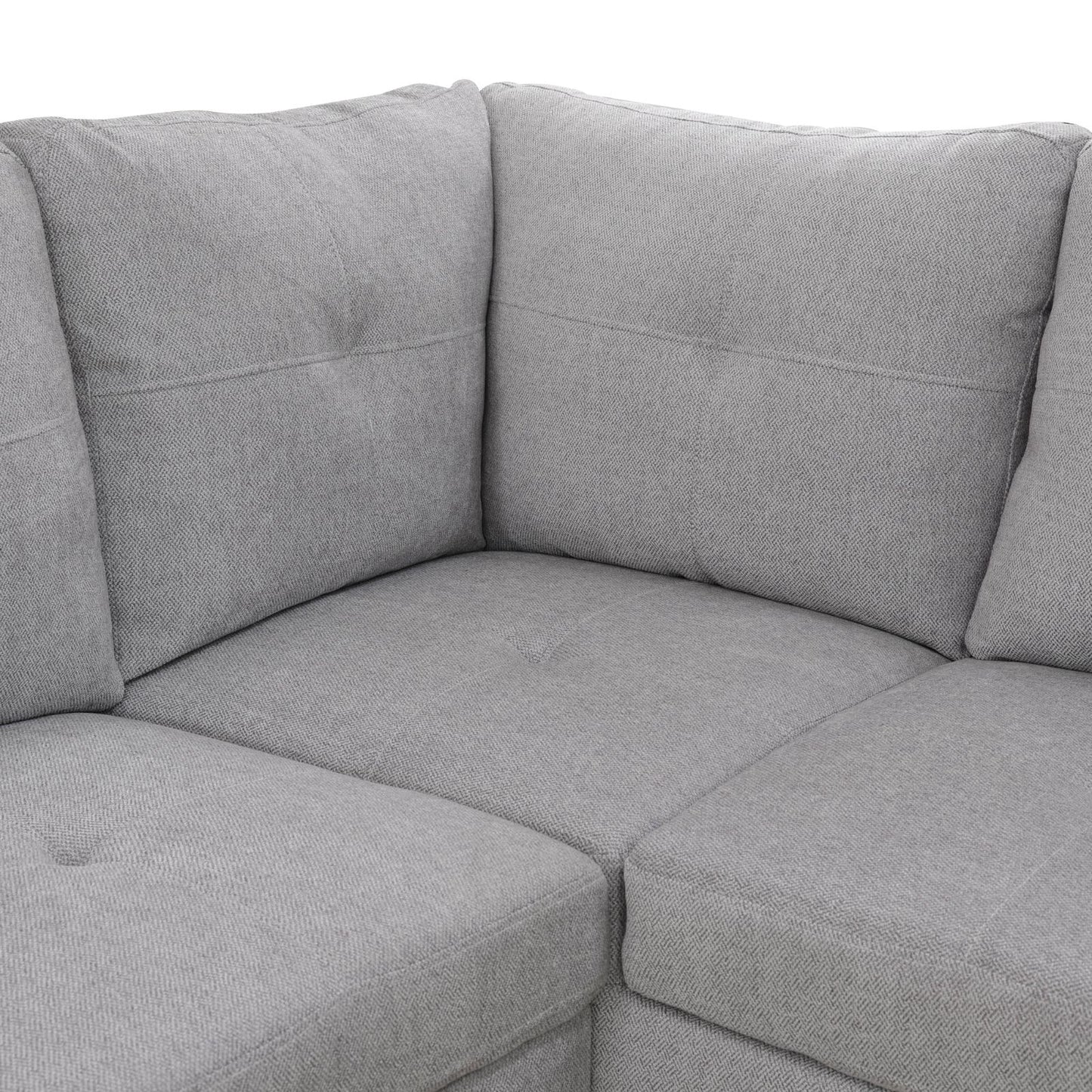 Closeup of a gray fabric sectional sofa with plush cushions and stitched detailing