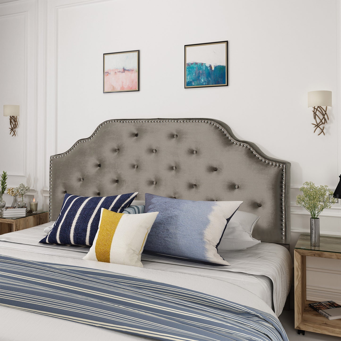 Tufted grey velvet headboard with silver nailhead trim and decorative pillows