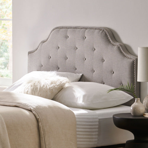 Tufted grey fabric headboard with nailhead trim and scalloped edges