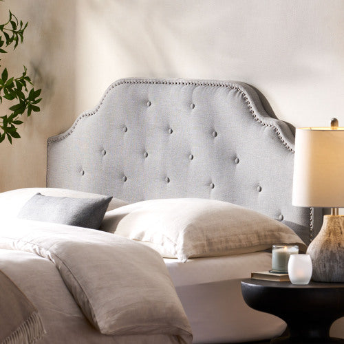 Light gray tufted headboard with nailhead trim