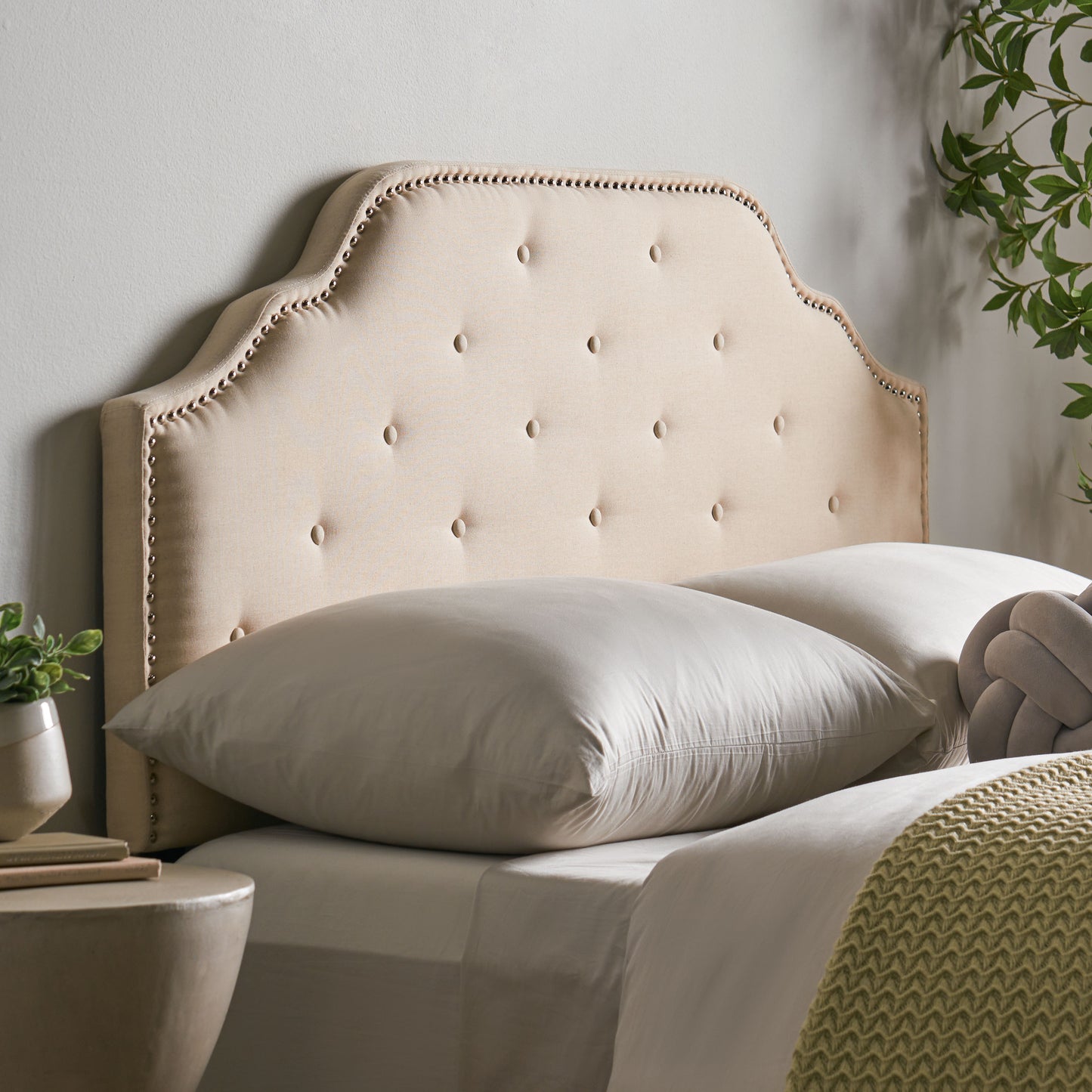 Tufted beige fabric headboard with nailhead trim detail