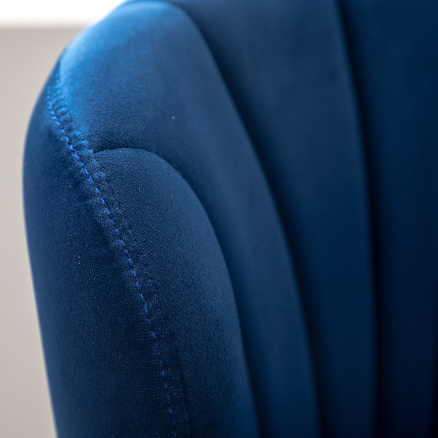 Closeup of plush navy velvet chair arm with contrast stitching