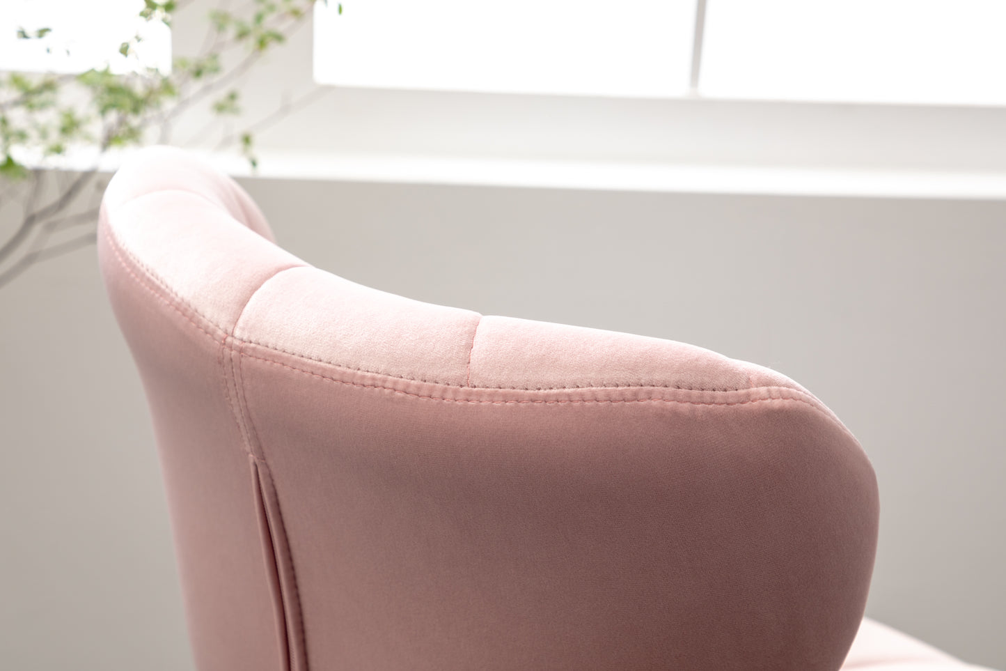 Closeup of plush pink velvet accent chair back with diamond stitching