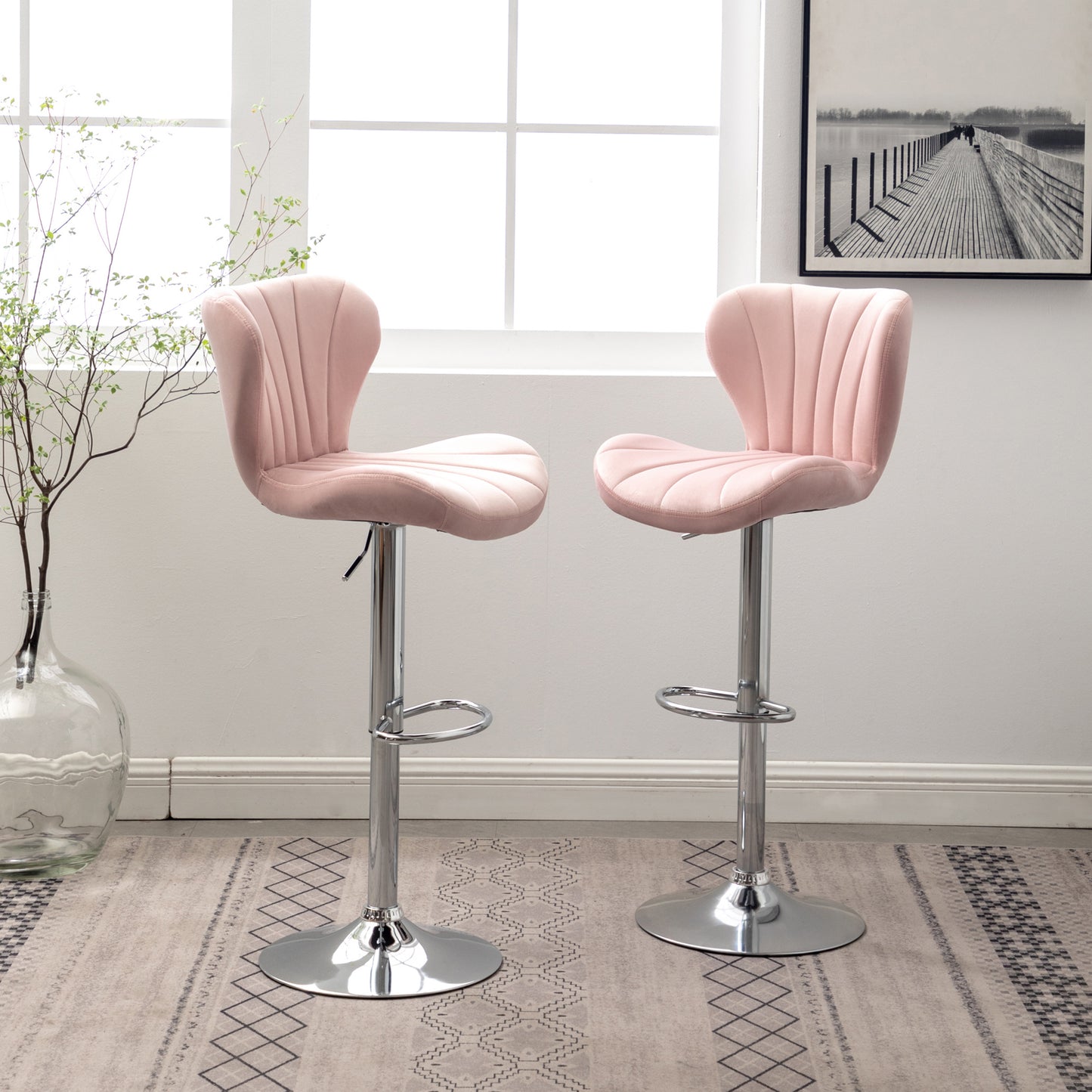 Two plush pink velvet bar stools with chrome bases and adjustable height are shown in a modern setting