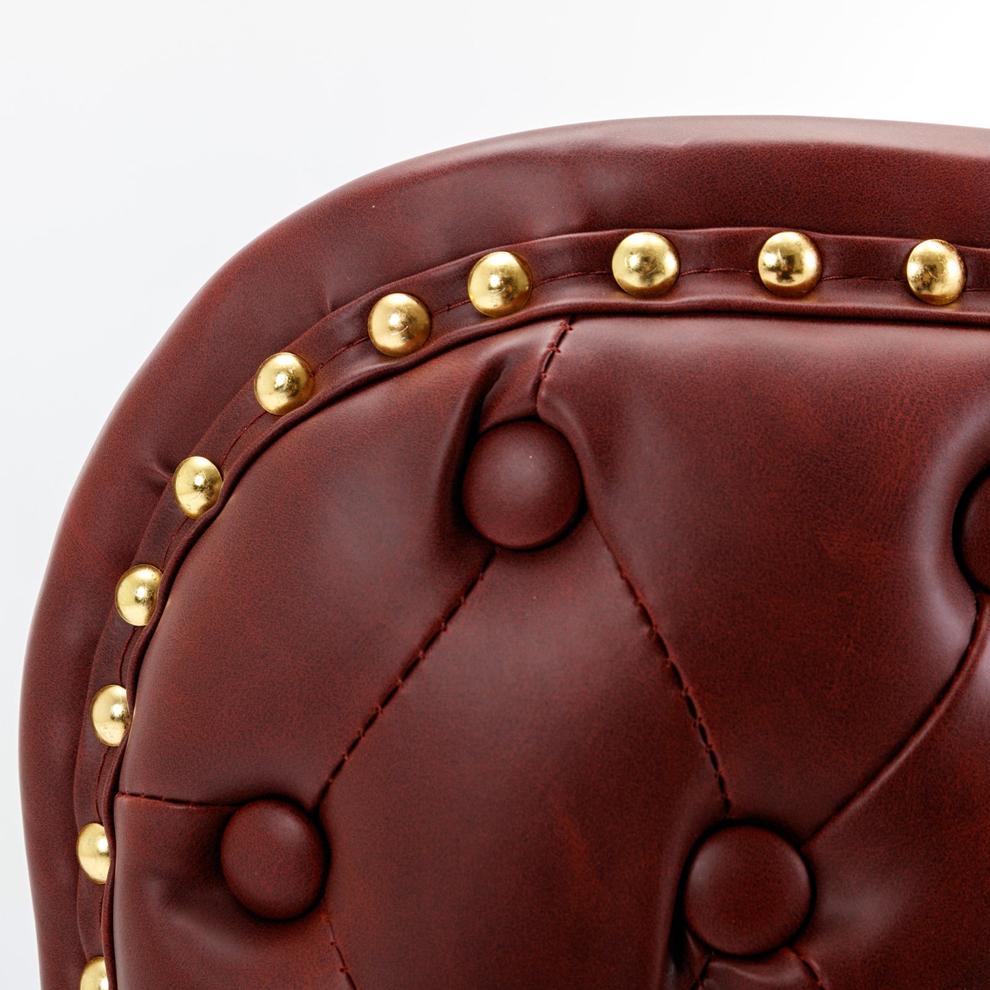 Detail of tufted mahogany leather armchair with brass nailhead trim