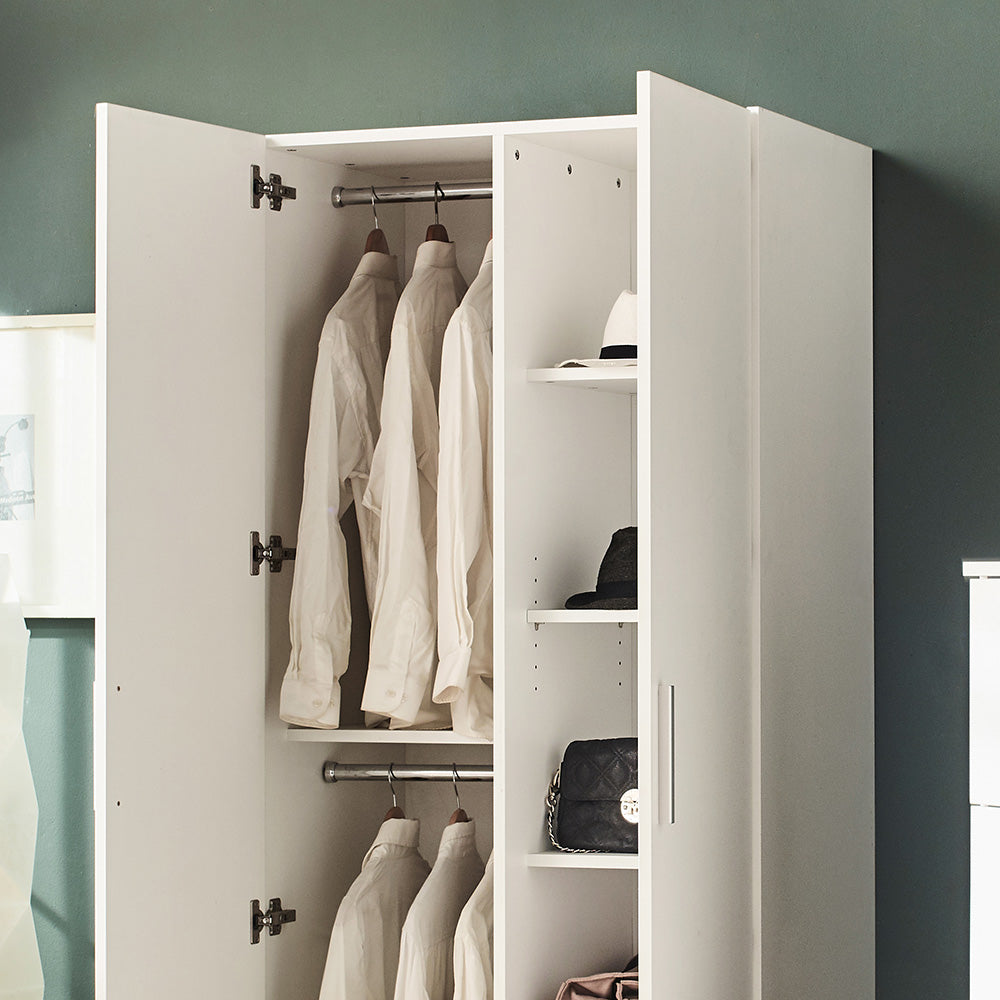White open wardrobe with hanging shirts and shelves holding hats and a quilted handbag
