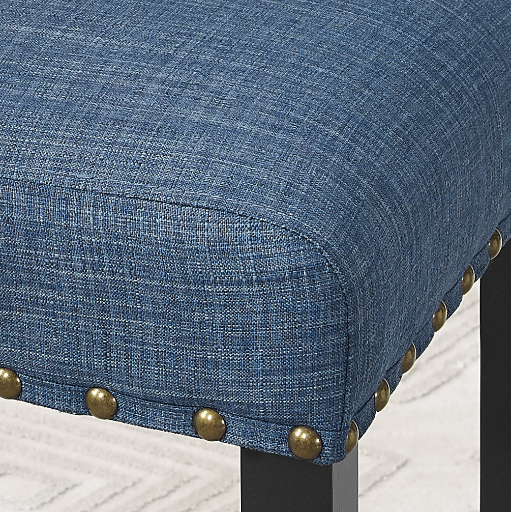 Closeup of upholstered navy blue accent chair cushion with brass nailhead trim