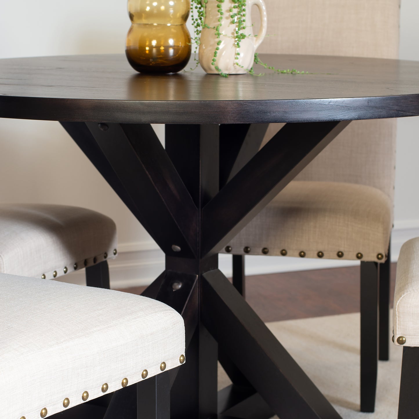 Dark wood round dining table with upholstered chairs and decorative vases