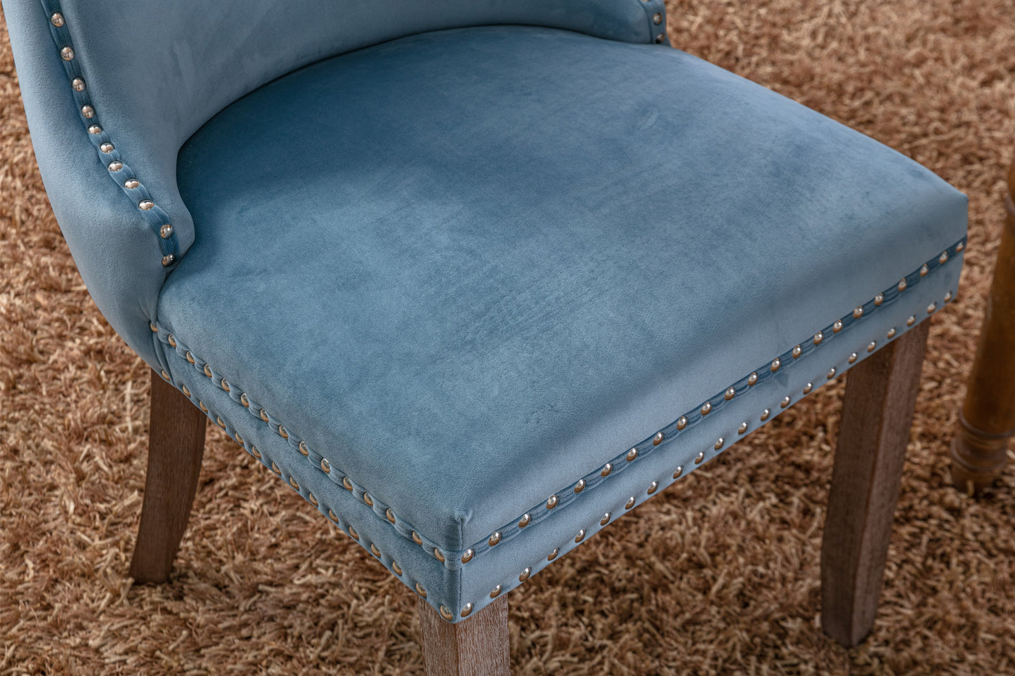 Blue velvet dining chair with brass nailhead trim and dark wood legs