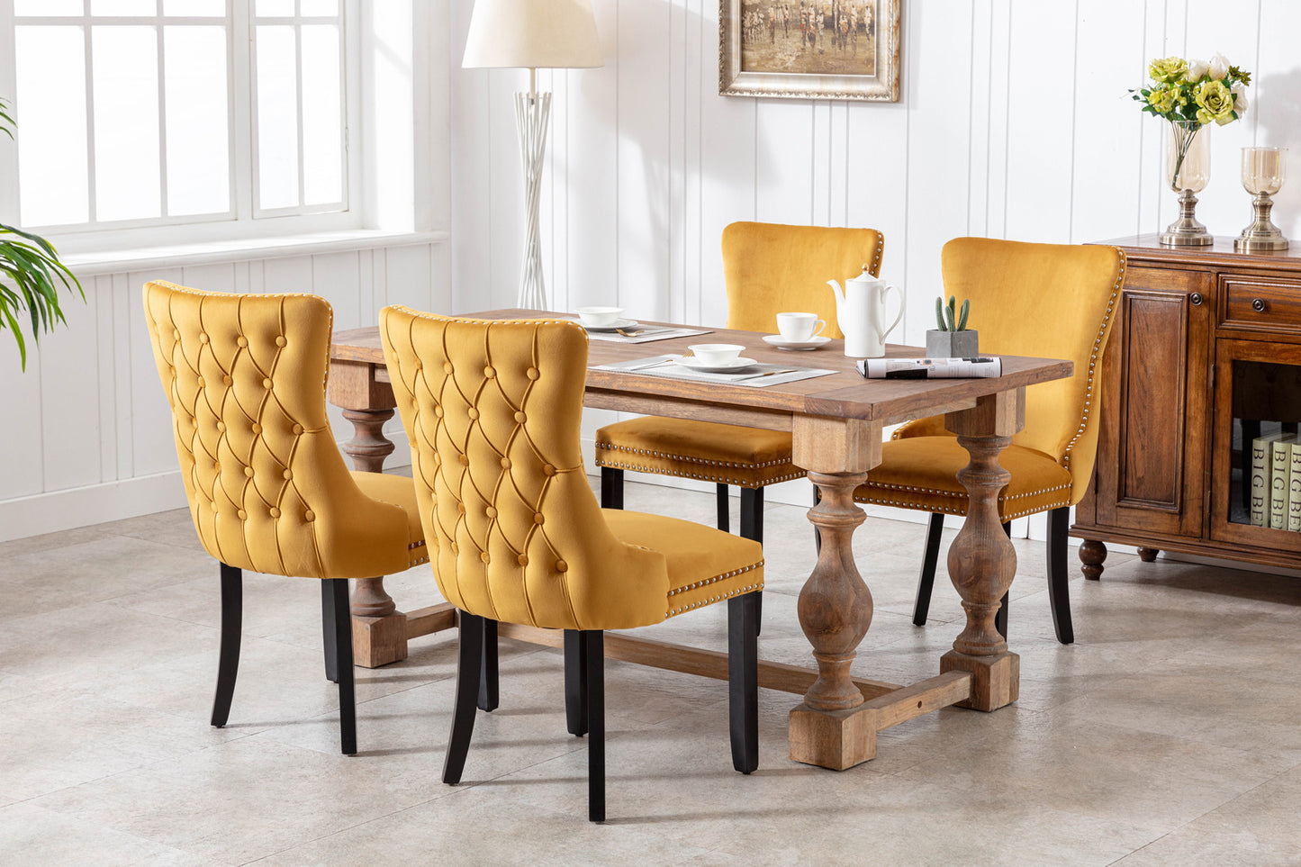 Tufted mustard yellow velvet dining chairs with nailhead trim around antique wood table