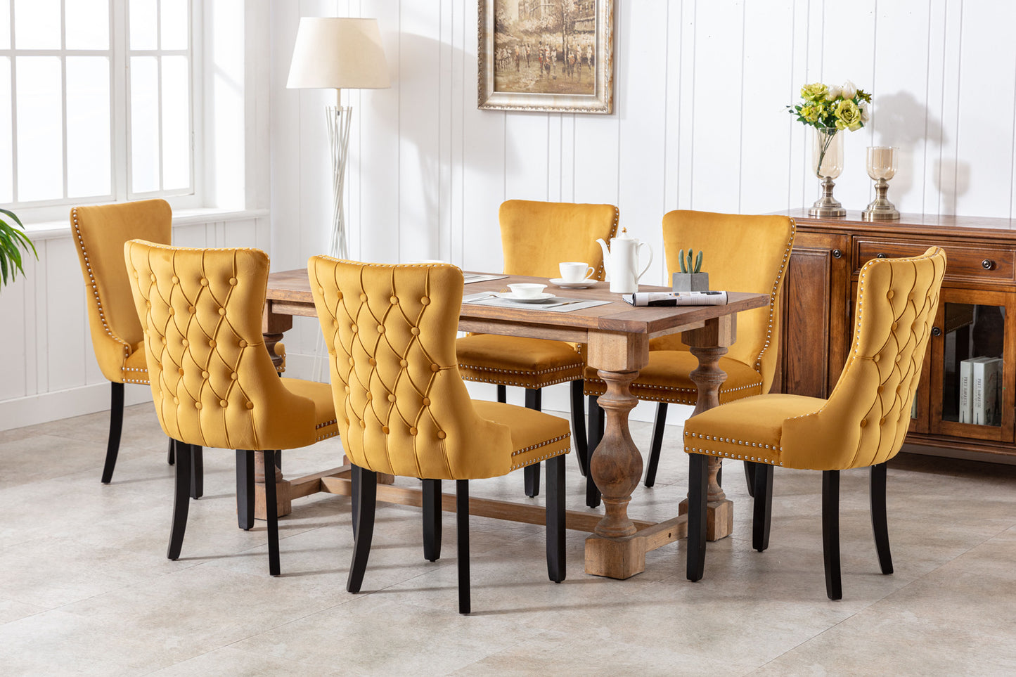 Yellow velvet dining chairs with tufted backs and nailhead trim around a wooden table