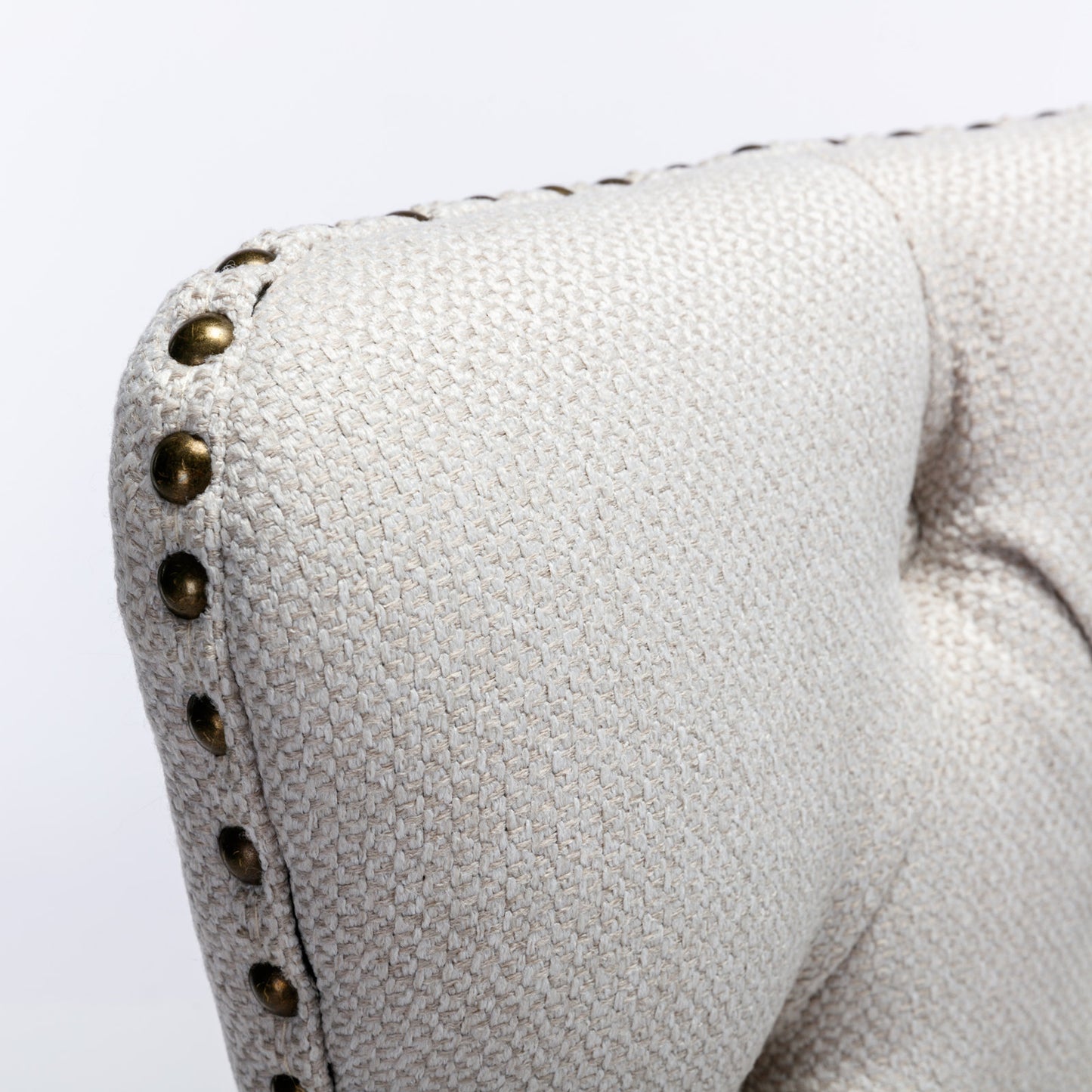 Beige textured fabric armchair with brass nailhead trim detail