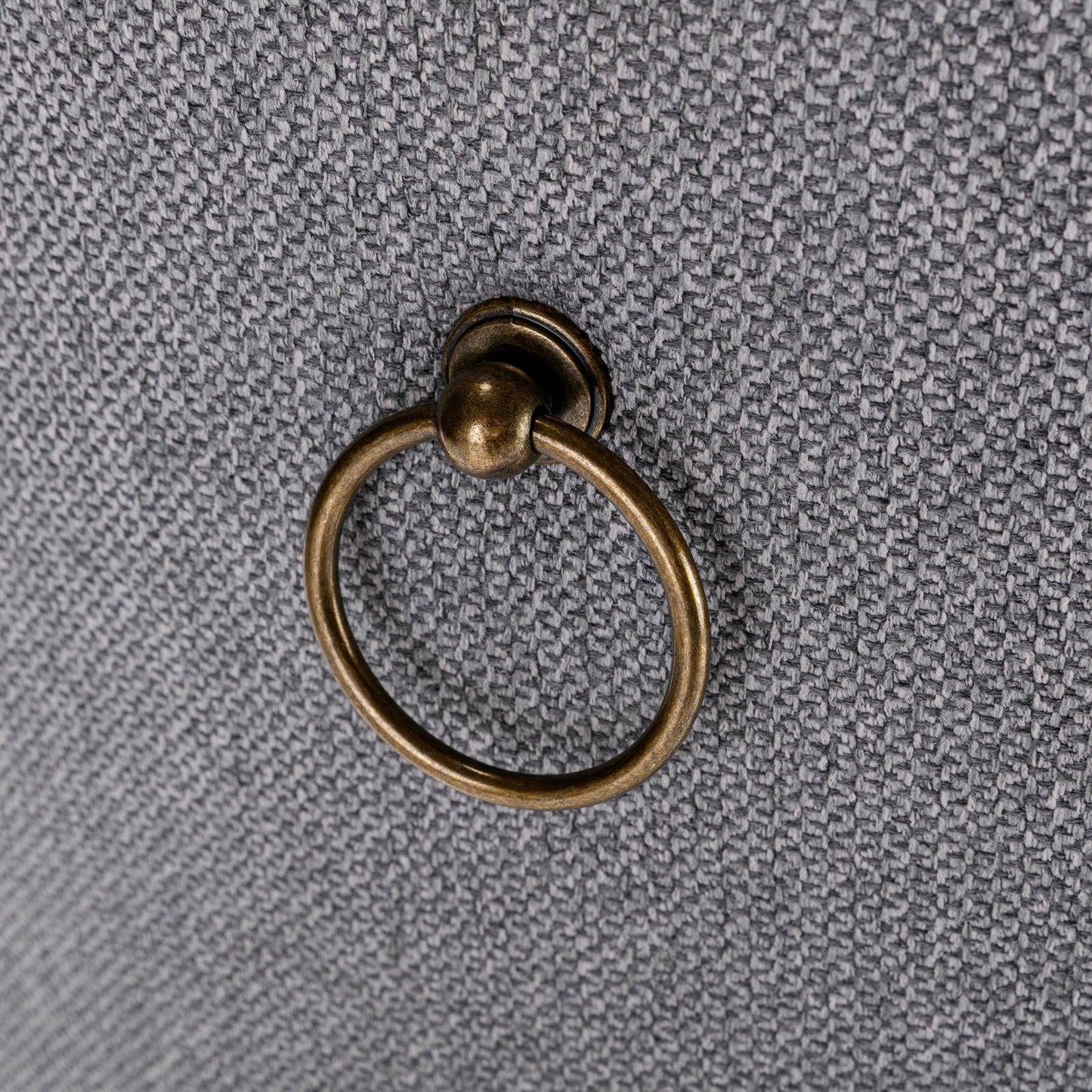 Antique brass ring pull on textured gray fabric drawer