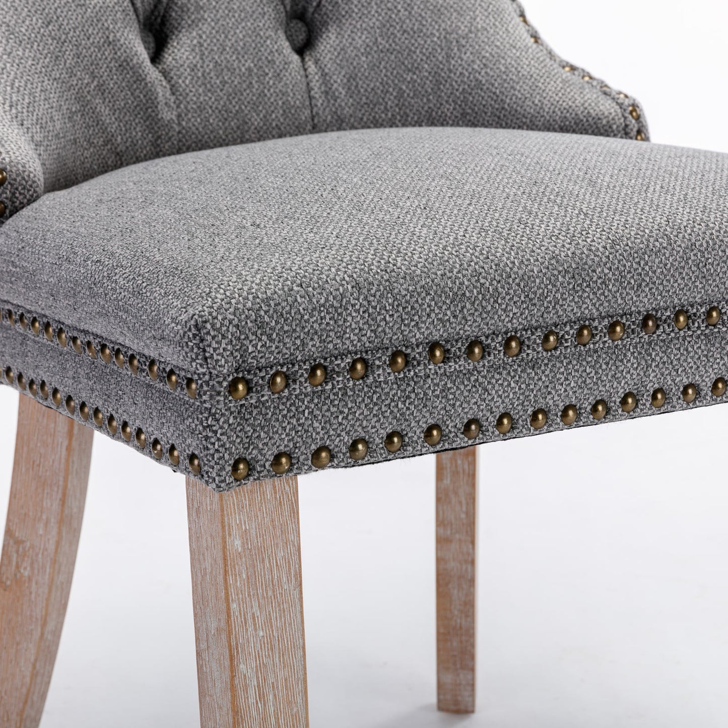 Tufted grey fabric armchair with antique brass nailhead trim and light wood legs