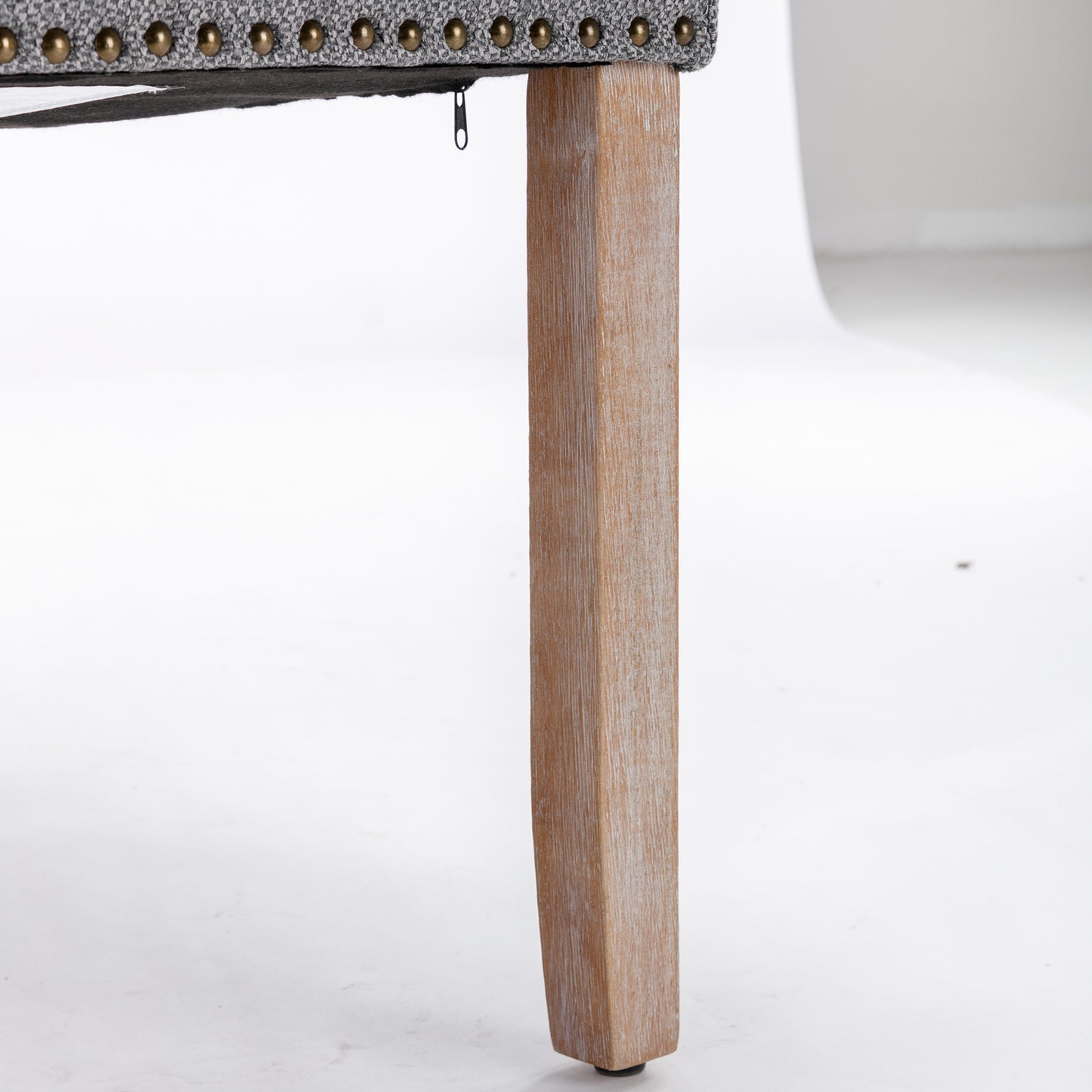 Upholstered armchair leg with rustic wood finish and brass nailhead trim