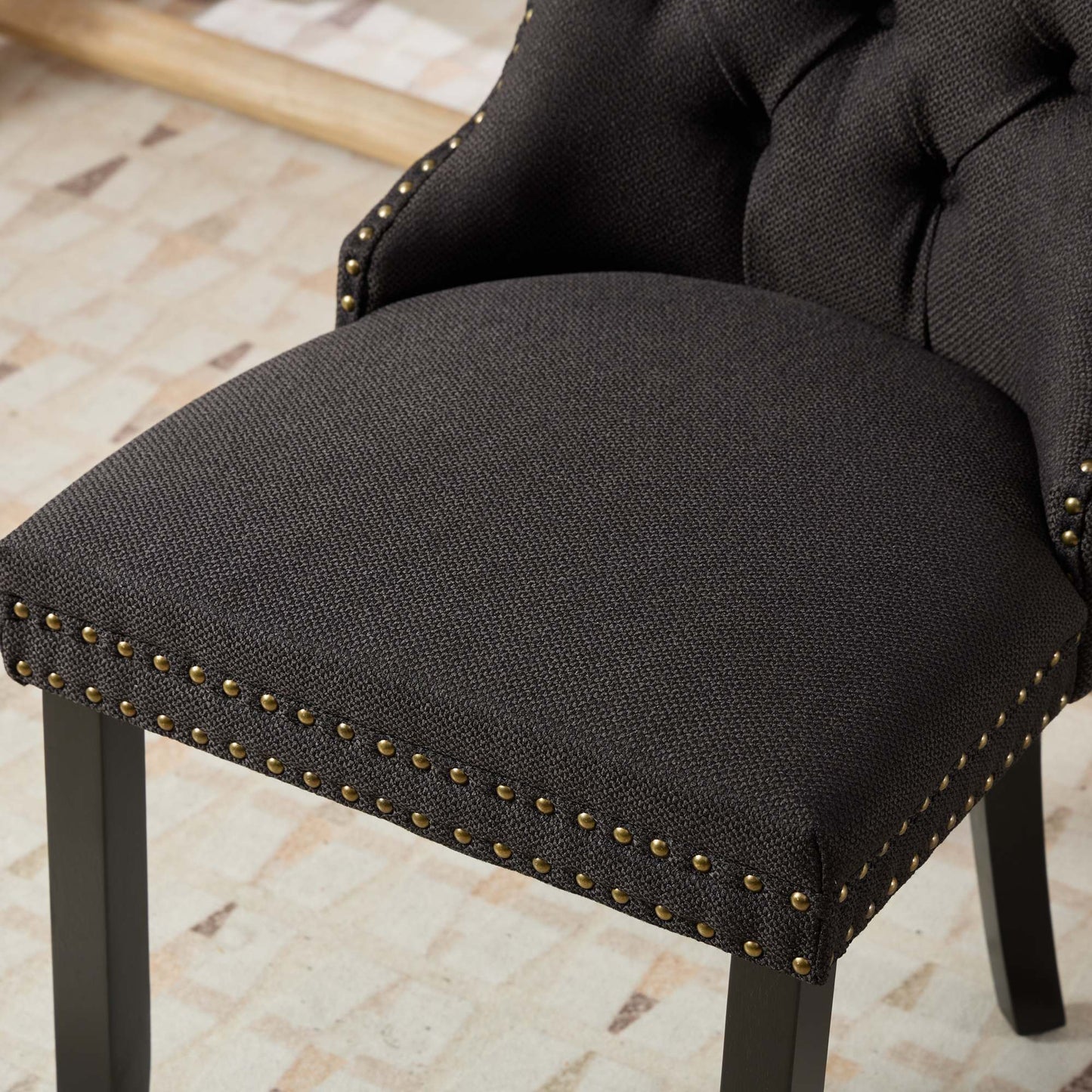 Dark gray upholstered dining chair with brass nailhead trim