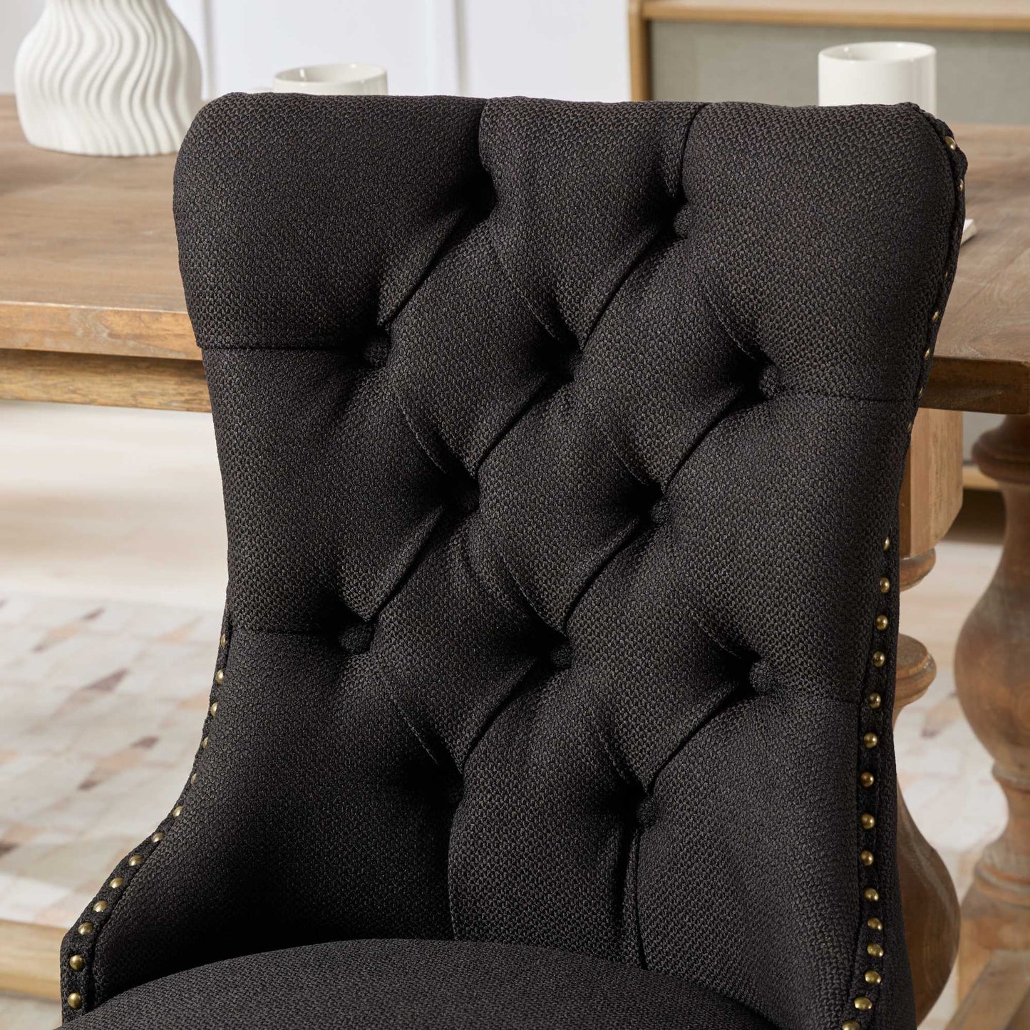 Black tufted upholstered dining chair with antique brass nailhead trim