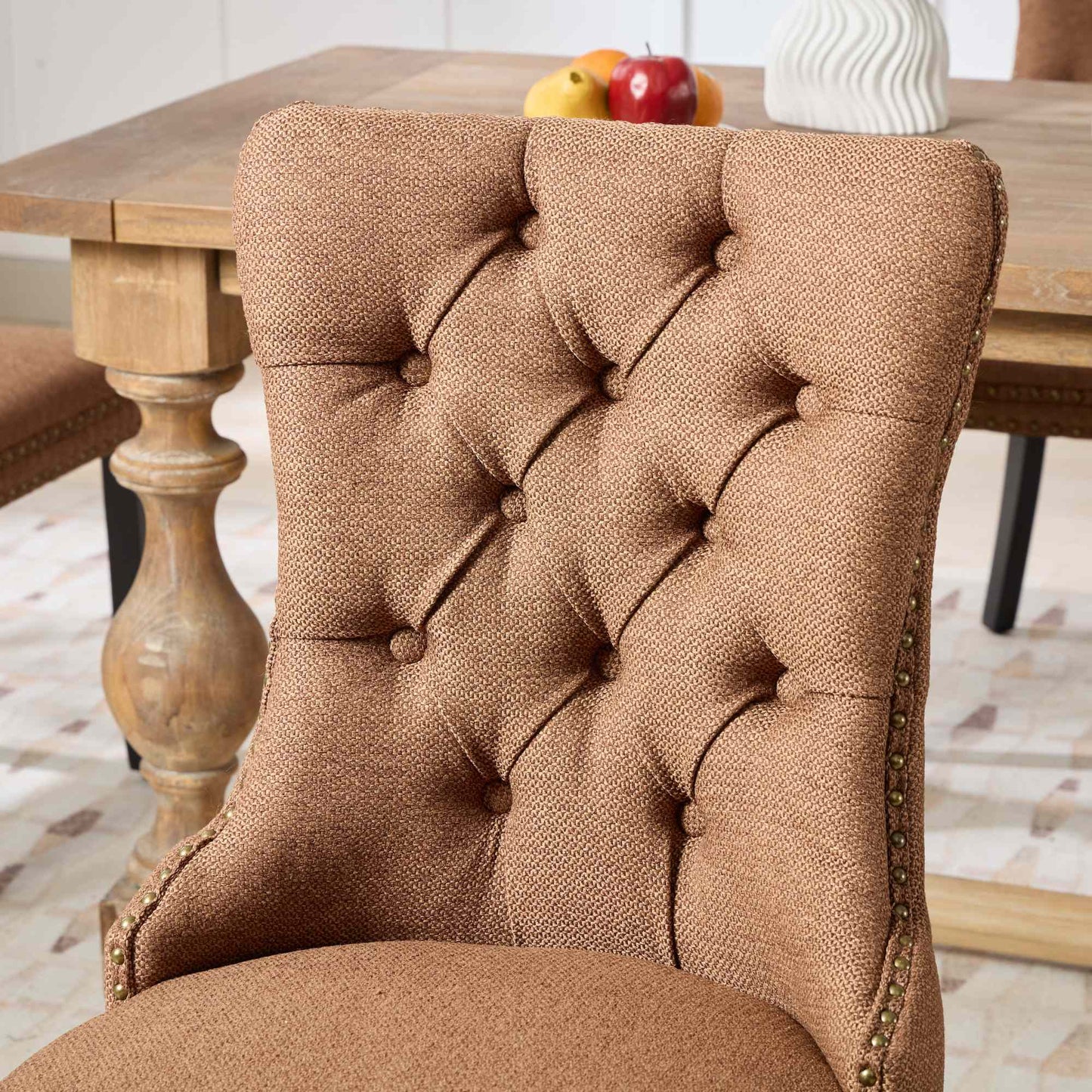 Tufted brown fabric dining chair with antique brass nailhead trim