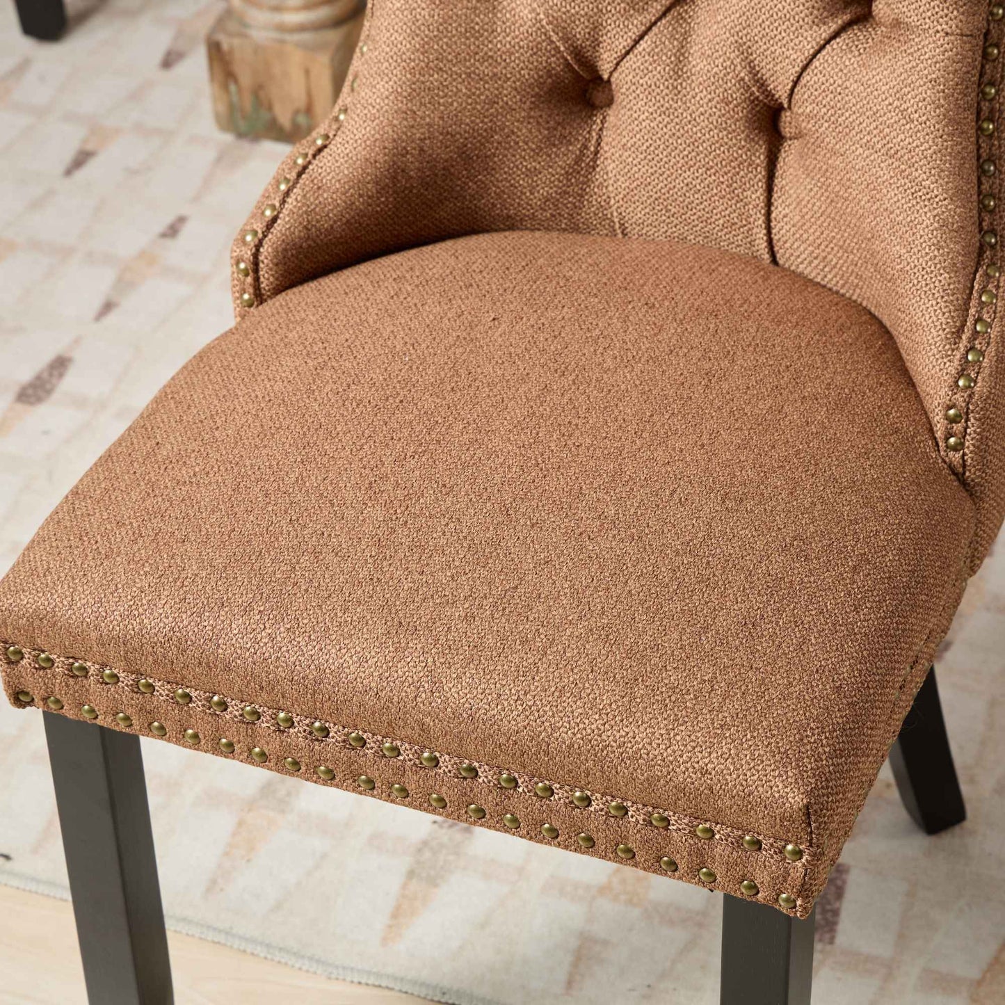 Tufted bronze fabric accent chair with brass nailhead trim and dark wood legs
