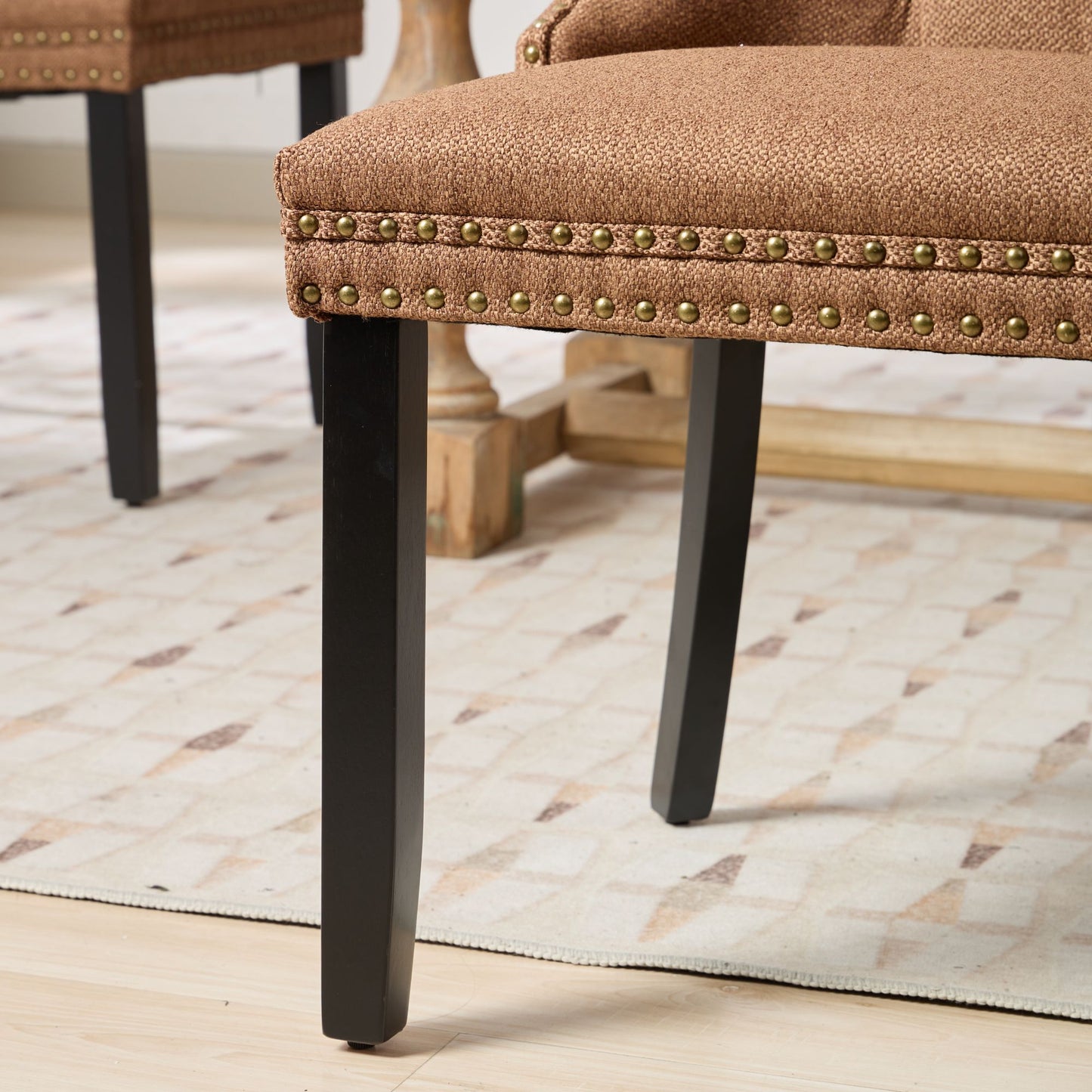 Brown fabric dining chair with nailhead trim and black legs