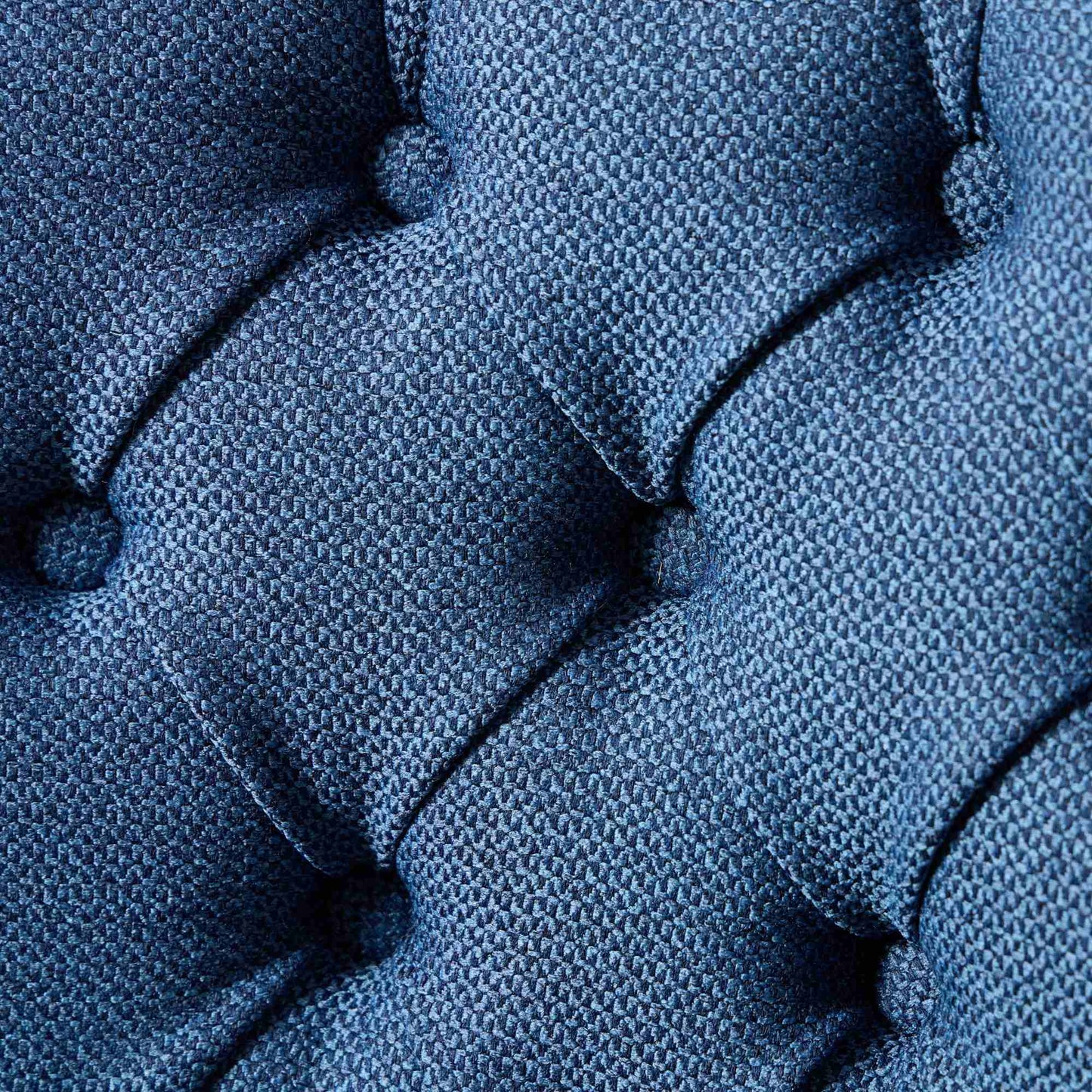 Closeup of deep blue textured upholstery fabric with tufting