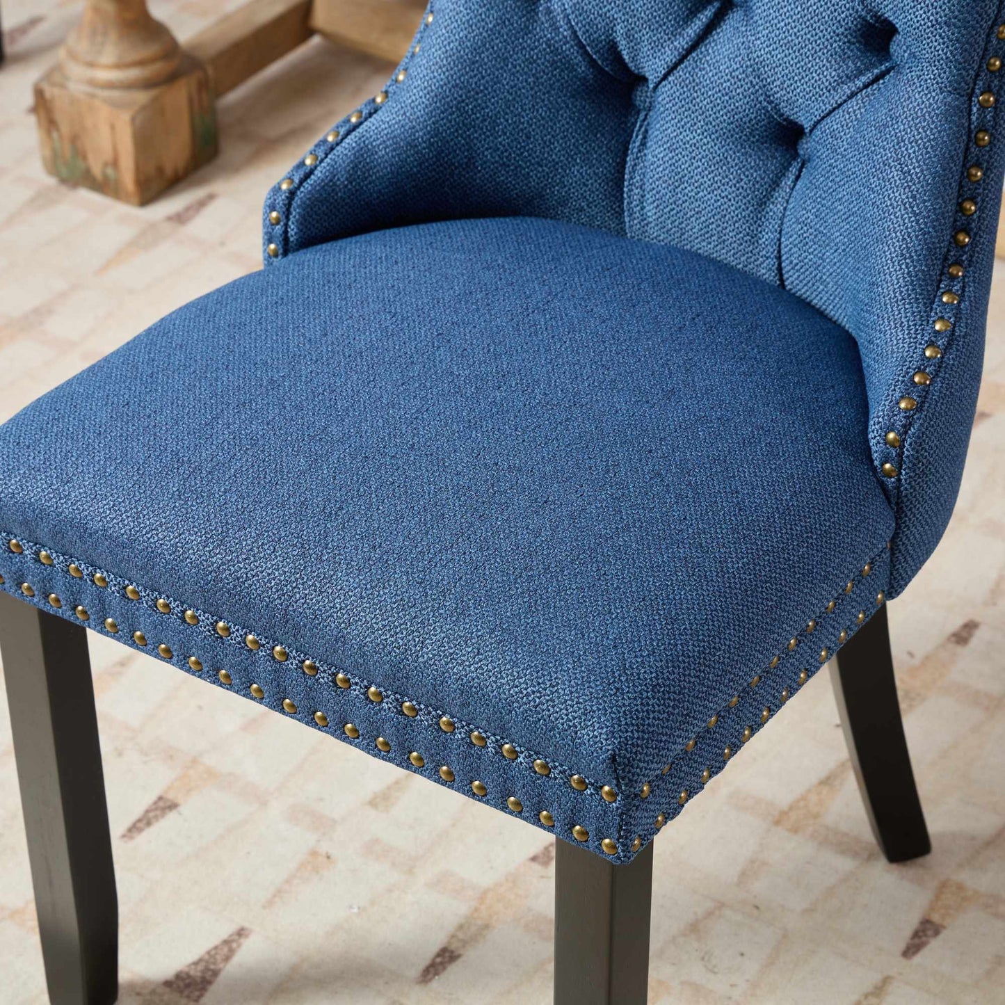 Blue upholstered dining chair with tufted back and brass nailhead trim
