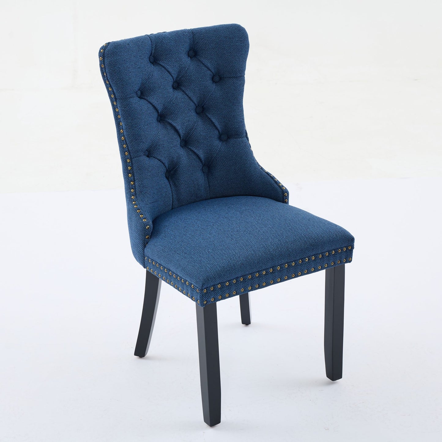 Deep blue upholstered dining chair with button tufting and brass nailhead trim