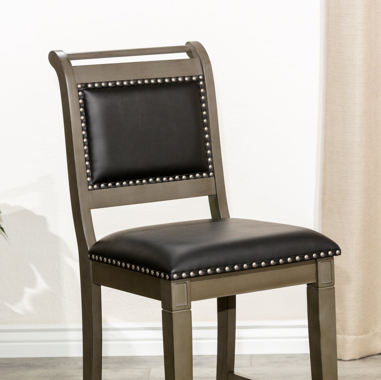 Gray wooden bar stool with black leather seat and silver nailhead trim