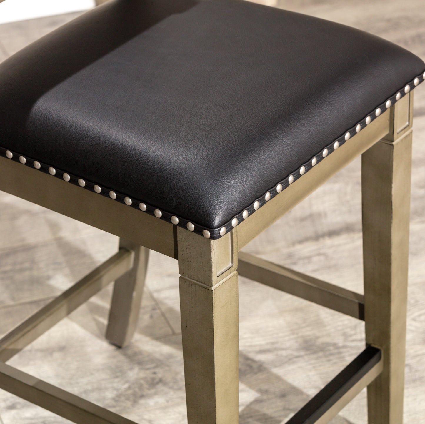 Black faux leather counter stool with silver nailhead trim and distressed wood frame