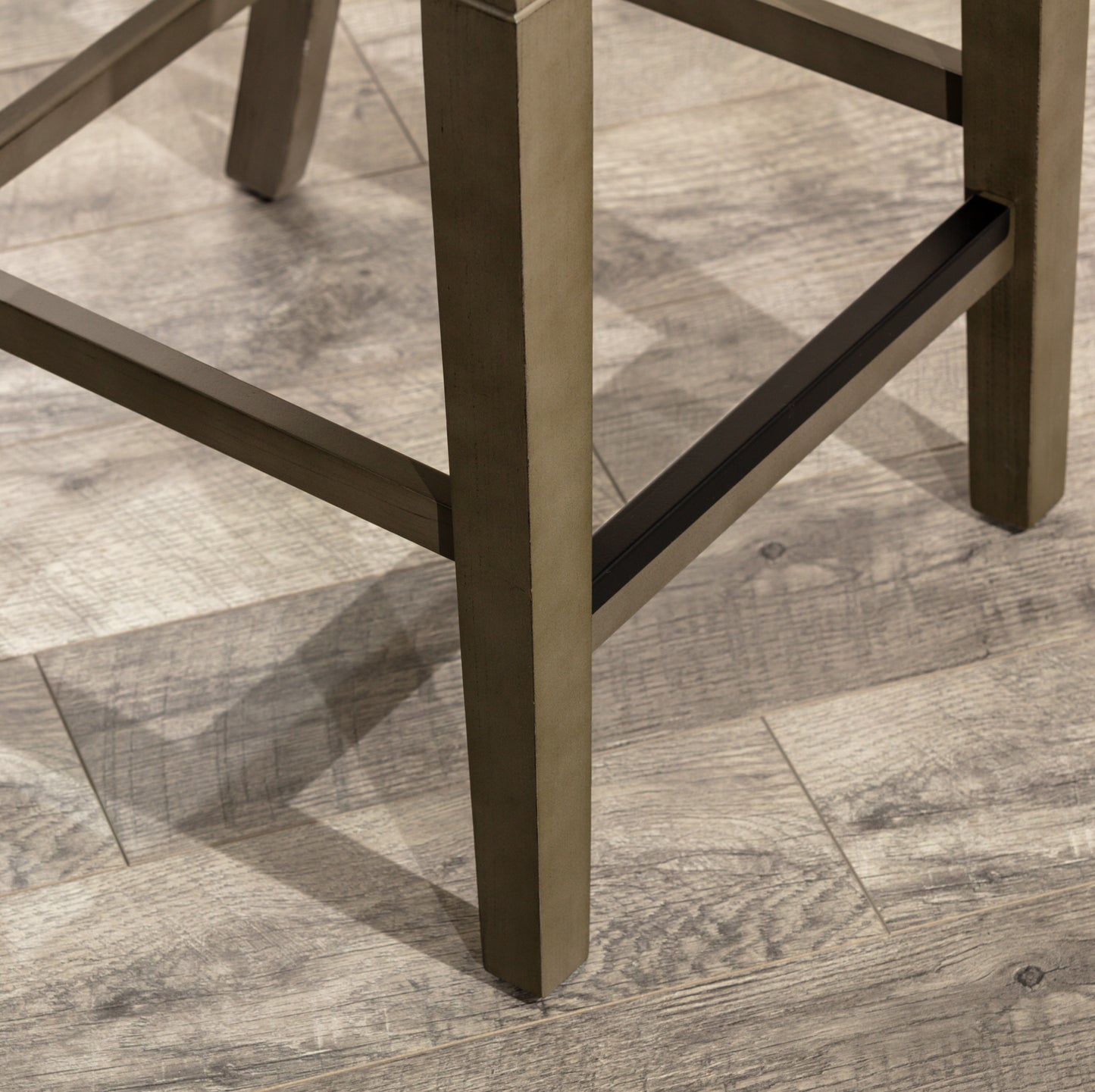 Close up of dark wood bar stool legs on a distressed wood floor