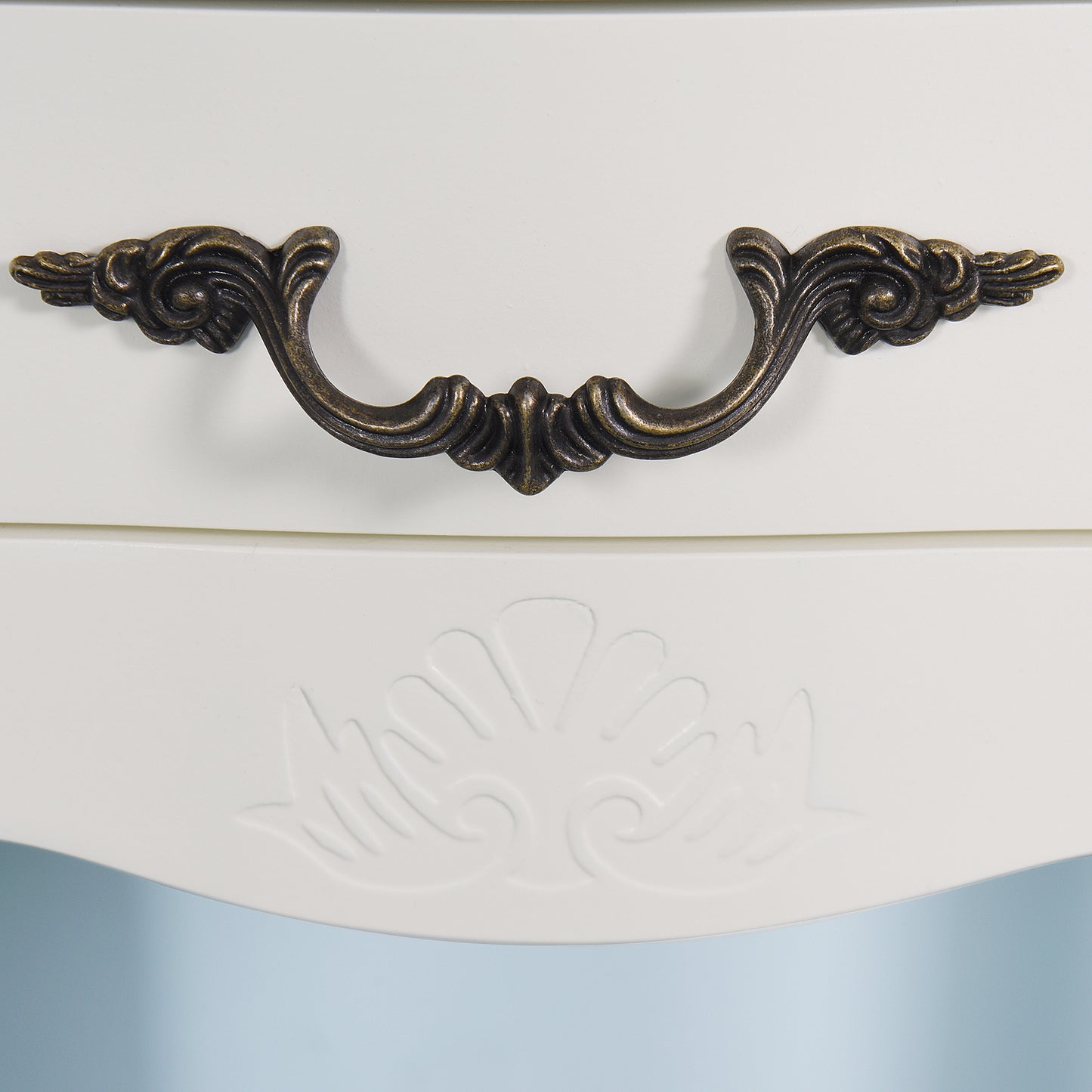 Antique brass ornate drawer pull on a white dresser