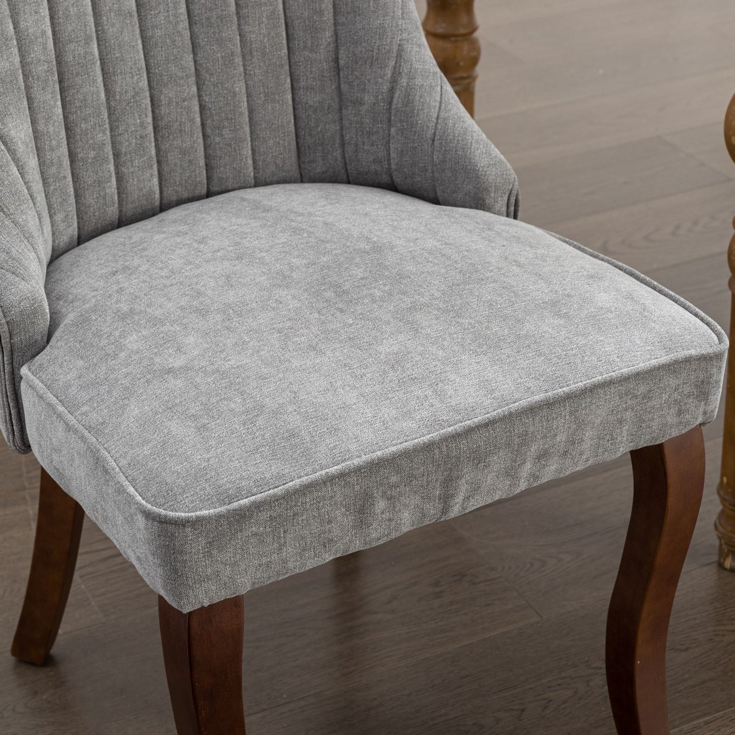 Plush grey upholstered dining chair with button tufting and dark wooden legs