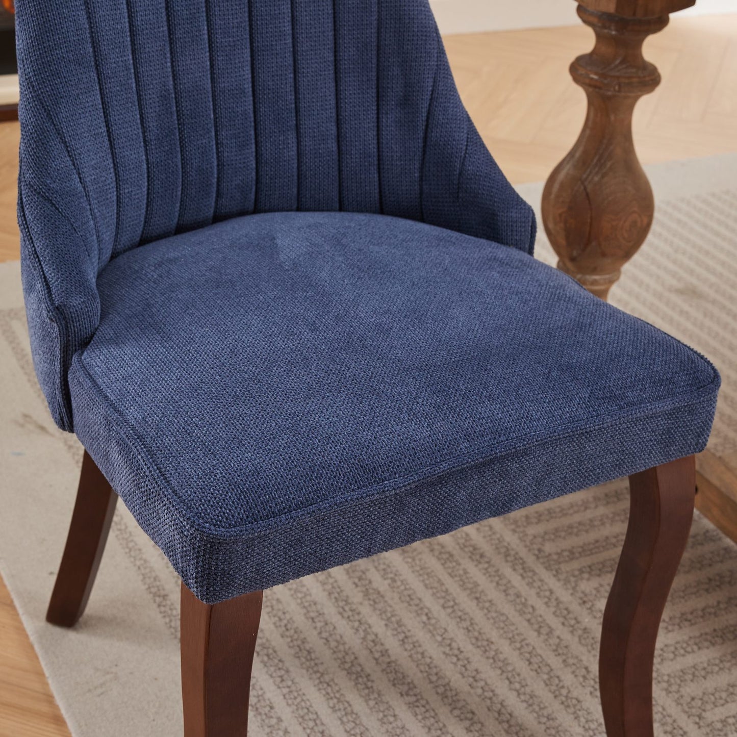 Closeup of a navy blue upholstered dining chair with channel tufting on the backrest